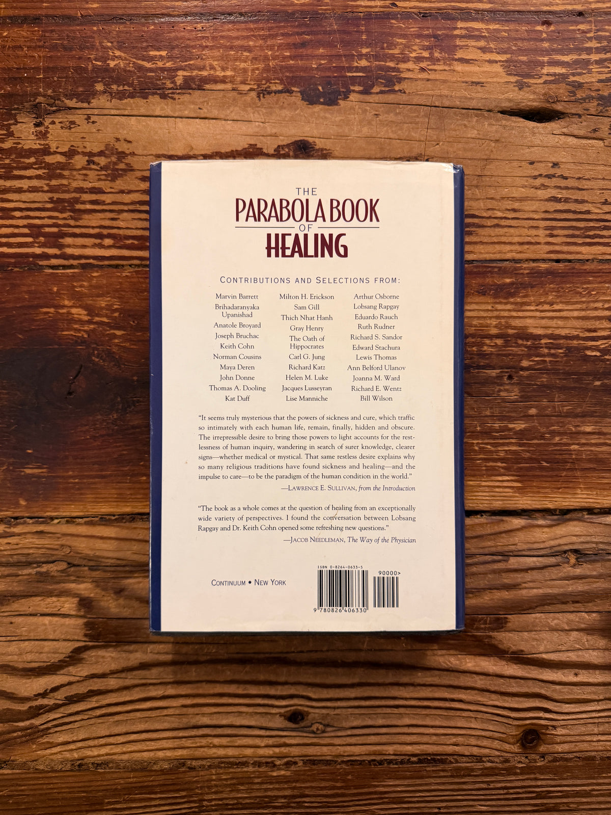 Back cover of a book titled 'the Parabola book of healing' on a wooden surface