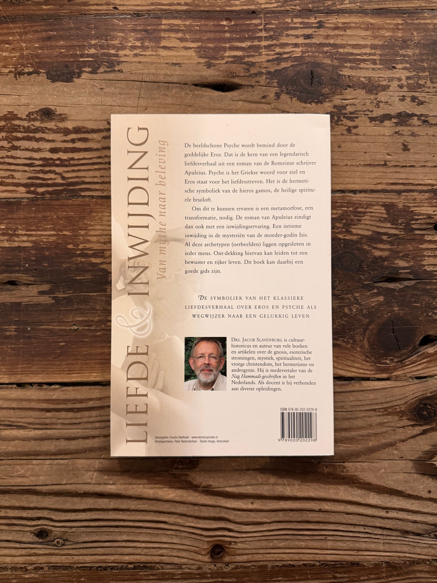 Achterkant van boek met de titel 'liefde & inwijding, van mythe naar beleving' door Jacob Slavenburg op een houten achtergrond