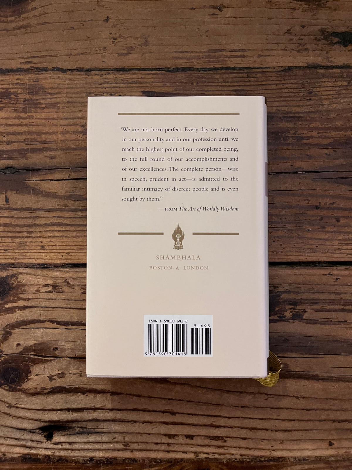 photo of the back cover of the book " the art of wordly wisdom"on a wooden background