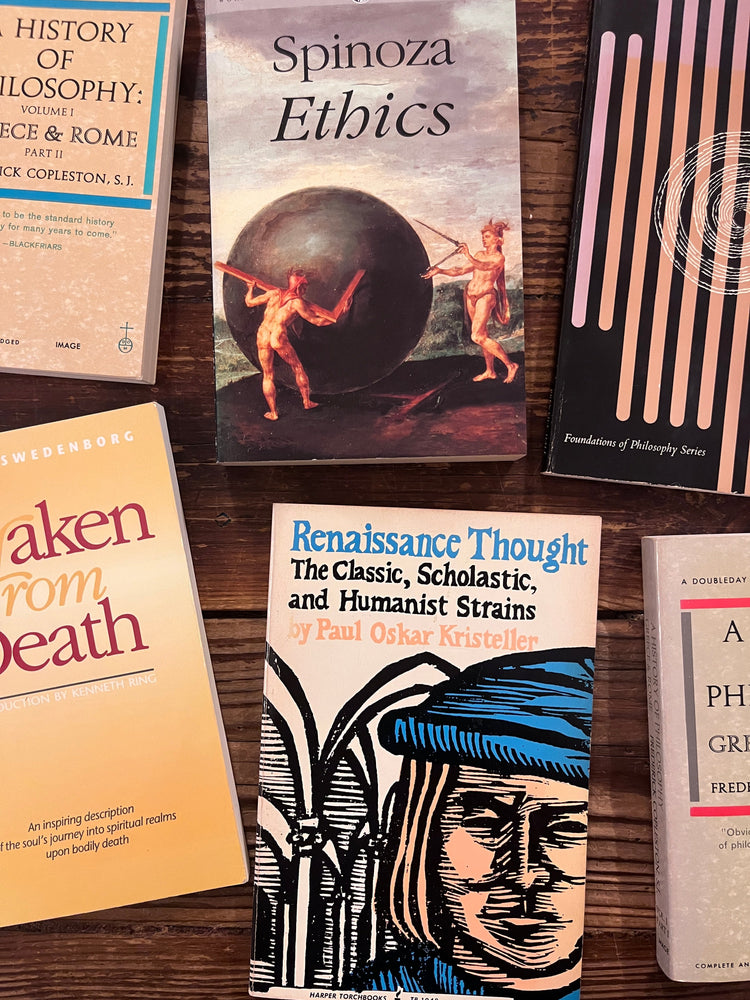 several books about classical and western philosophy laid out on a wooden surface 