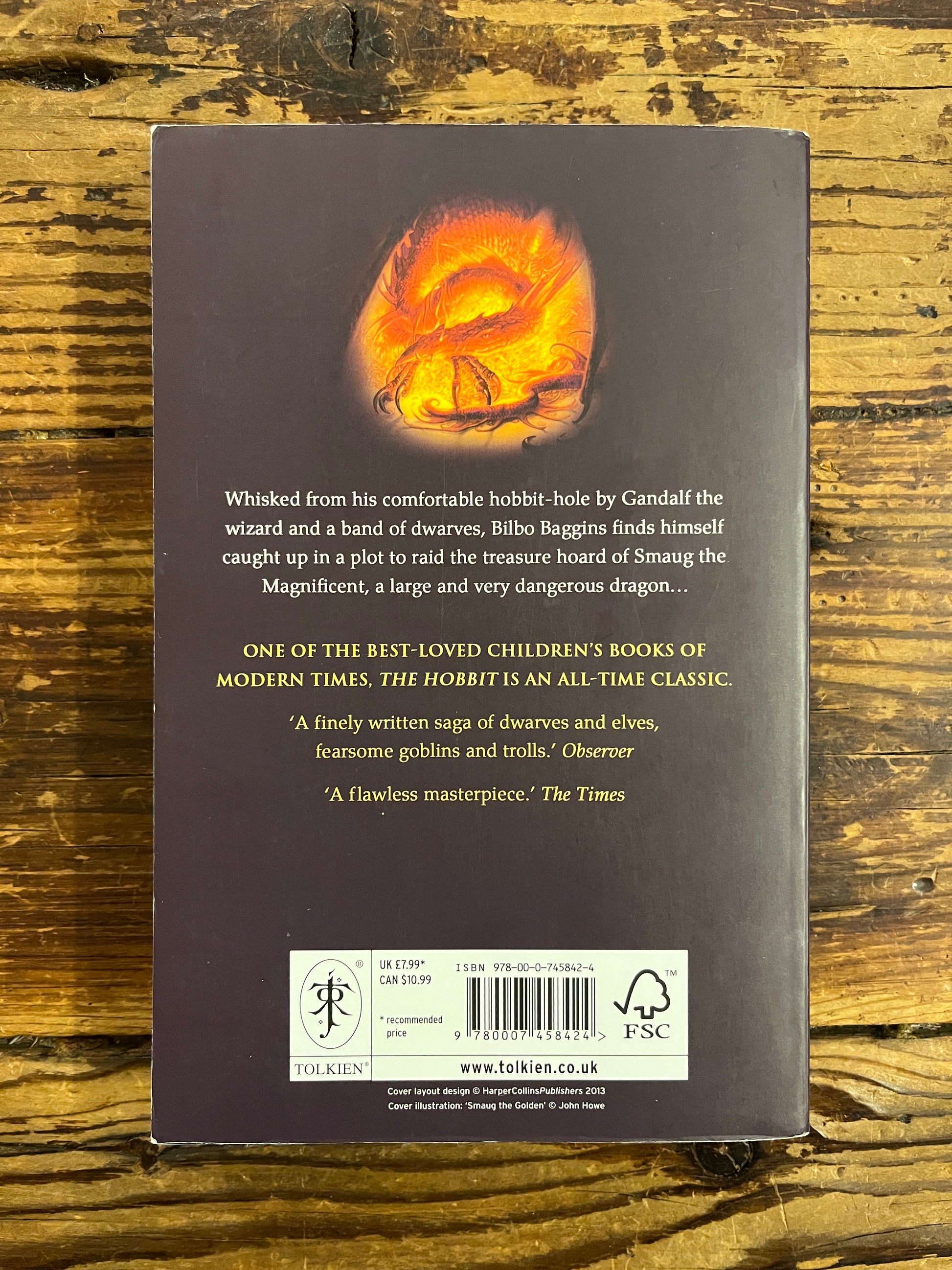 Back cover of book titled 'The Hobbit' by J.R.R. Tolkien on a wooden surface