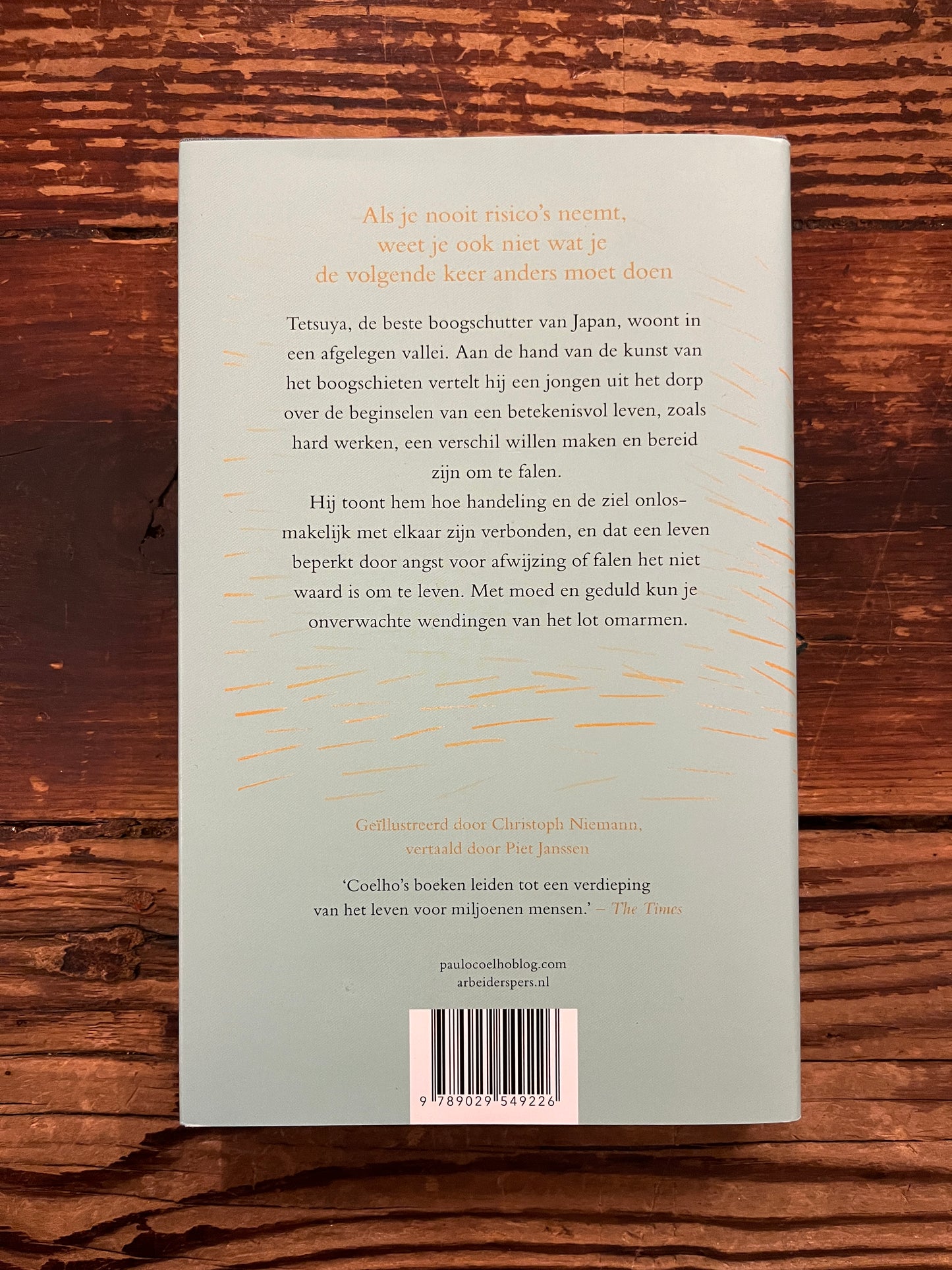 Achterkant van boek 'de weg van de boog' door Paulo Coelho op een houten achtergrond 