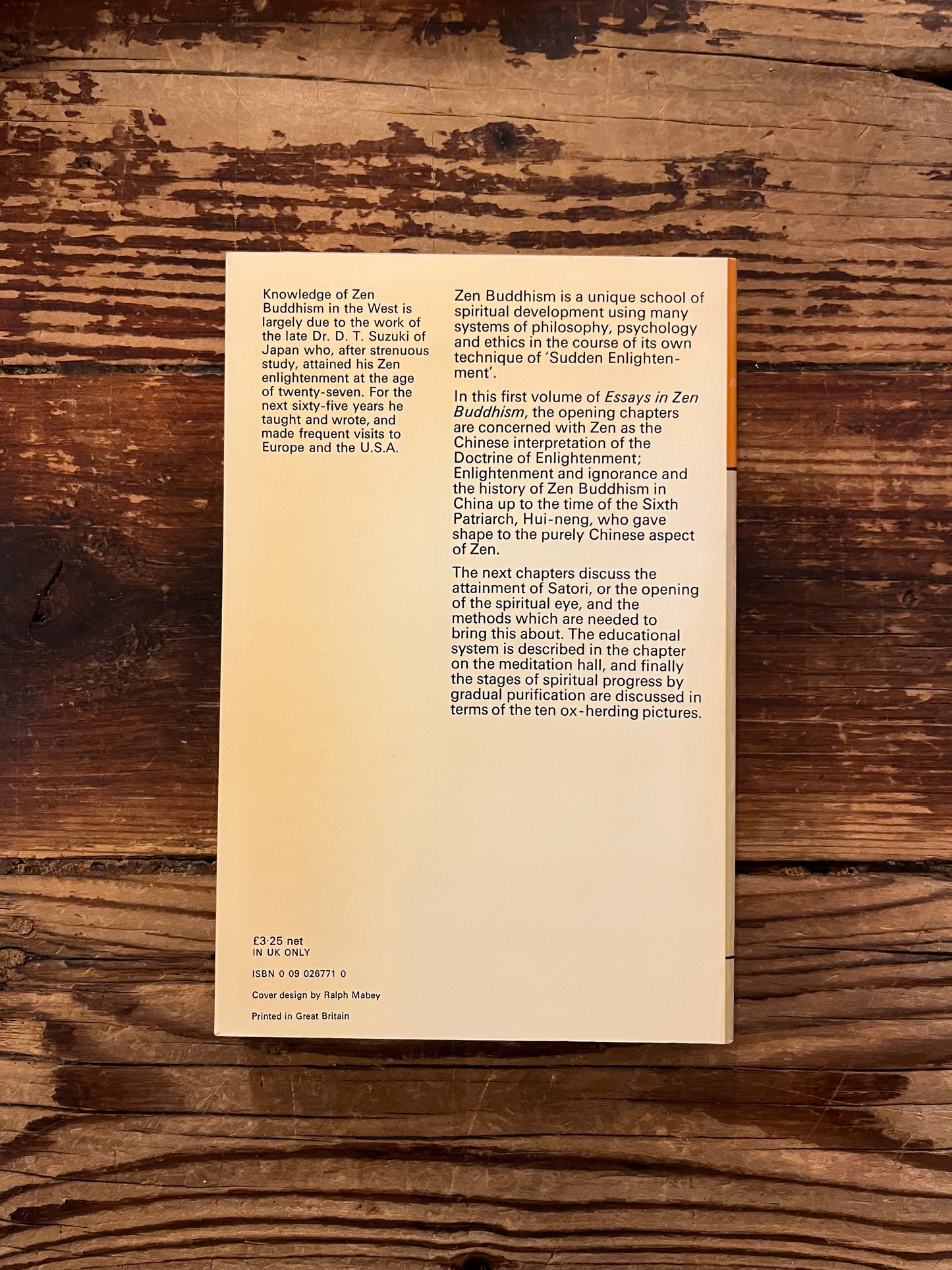 Back cover of book titled 'Essays in Zen Buddhism' by D.T. Suzuki on a wooden surface