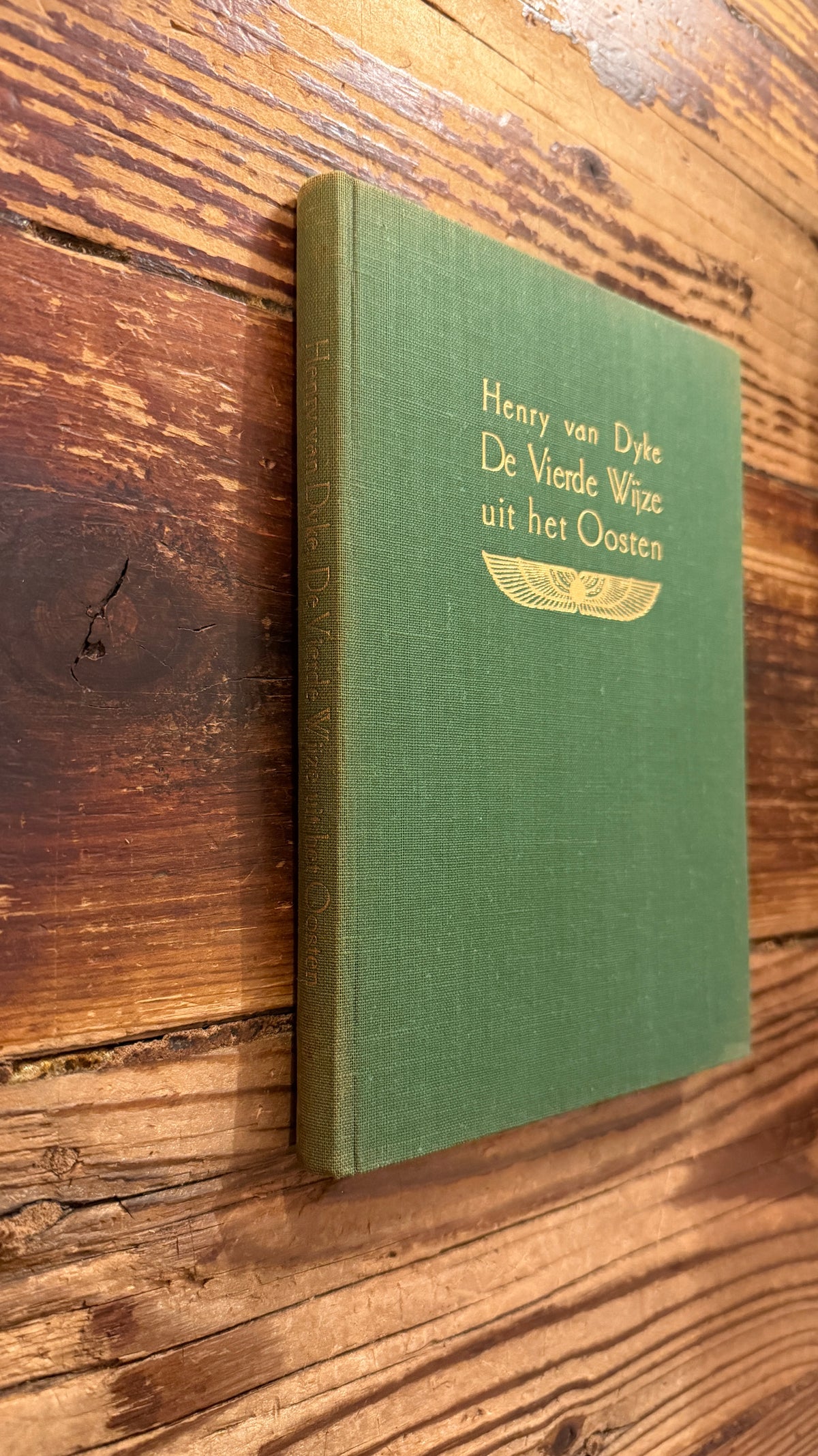 Voorkant  en rug van een boek met de titel 'De Vierde Wijze uit het Oosten' door Henry van Dyke op een houten achtergrond