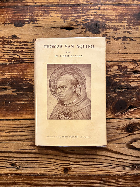 Voorkant van boek met de titel 'Thomas van Aquino' door Dr. Ferd. Sassen op een houten achtergrond 
