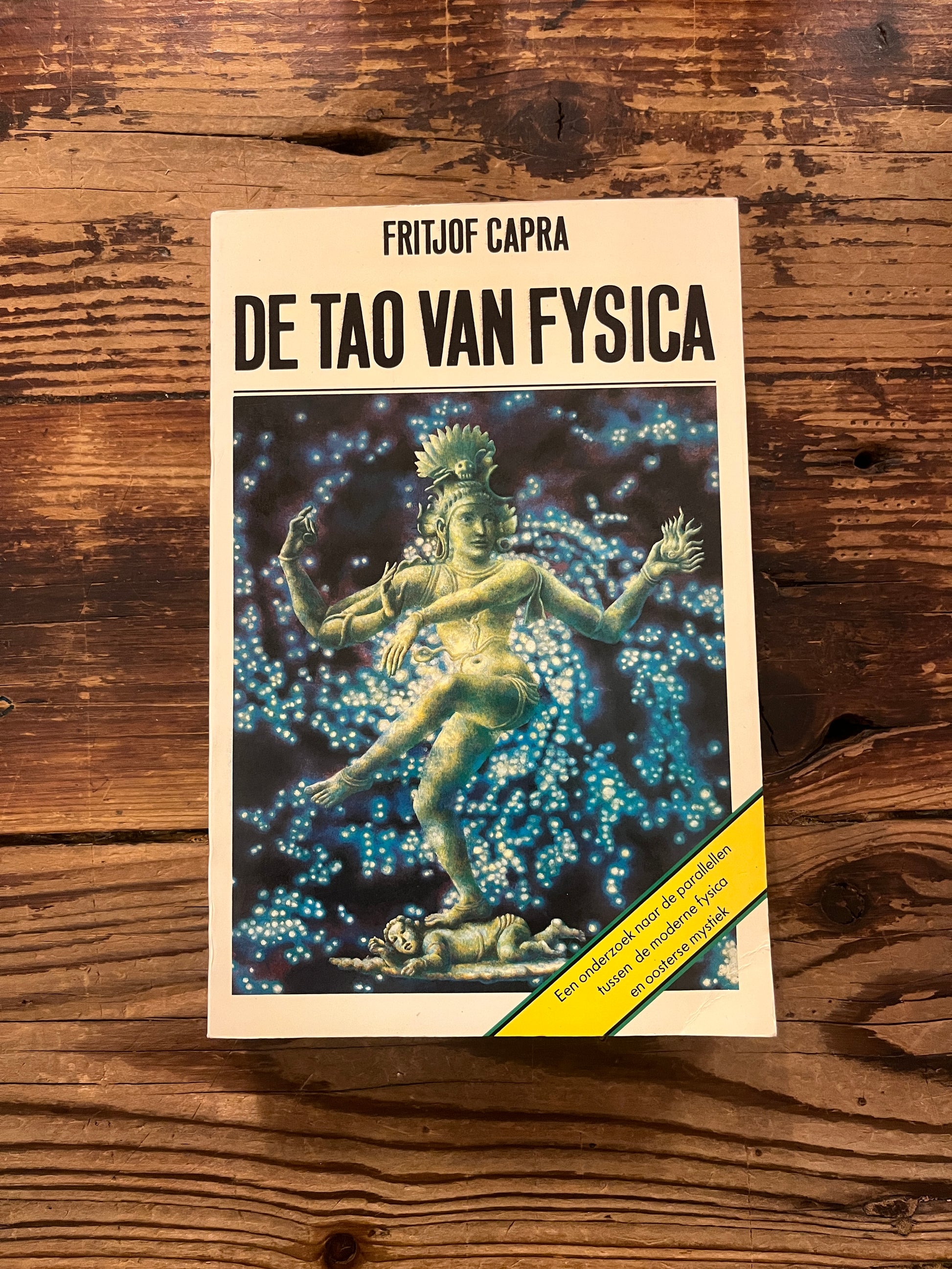 Boek met de titel 'de Tao van Fisica' door Fritjof Capra op een houten achtergrond 