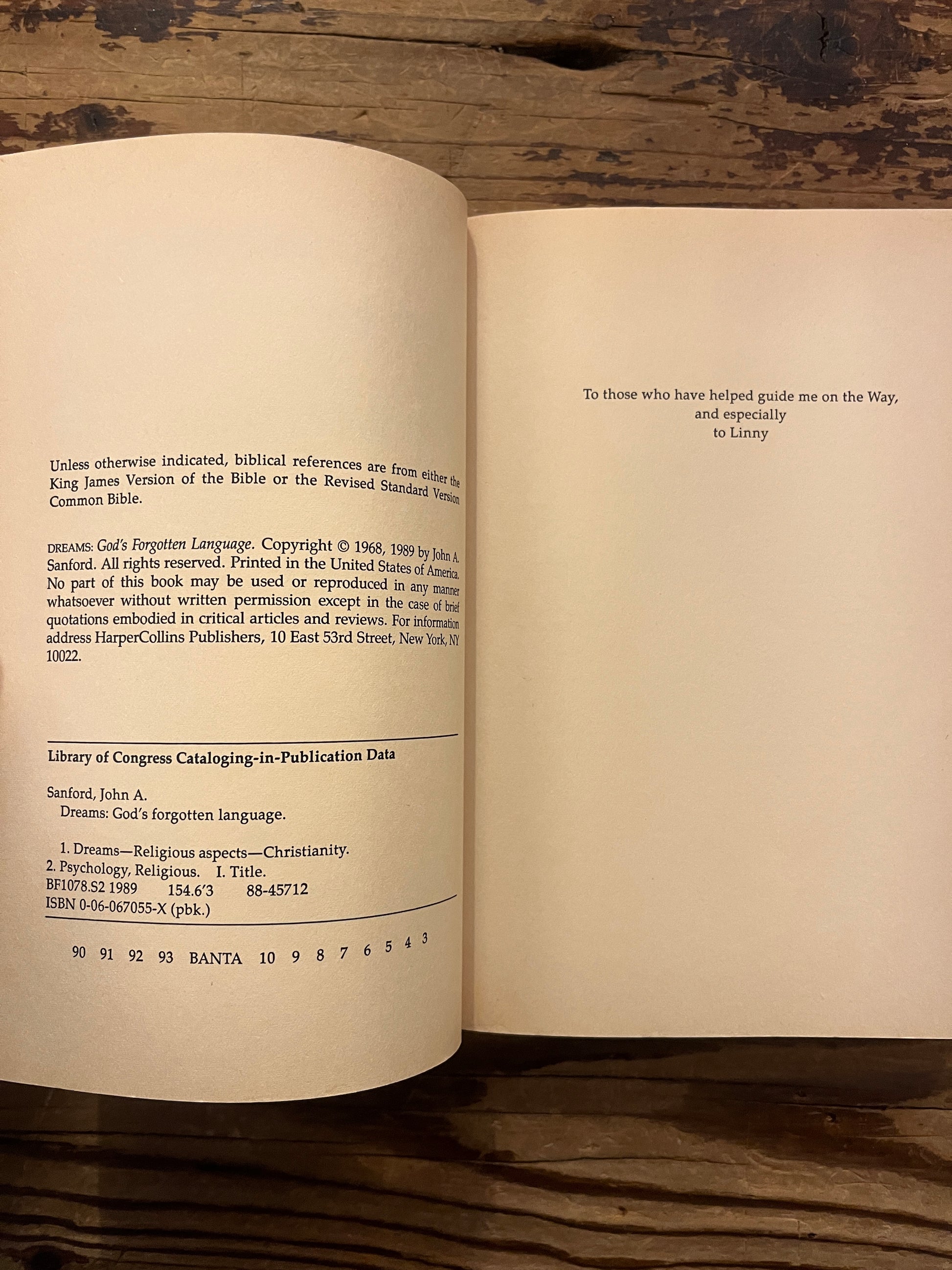 Open book titled 'Dreams: God's Forgotten Language' by John A. Sanford on a wooden surface