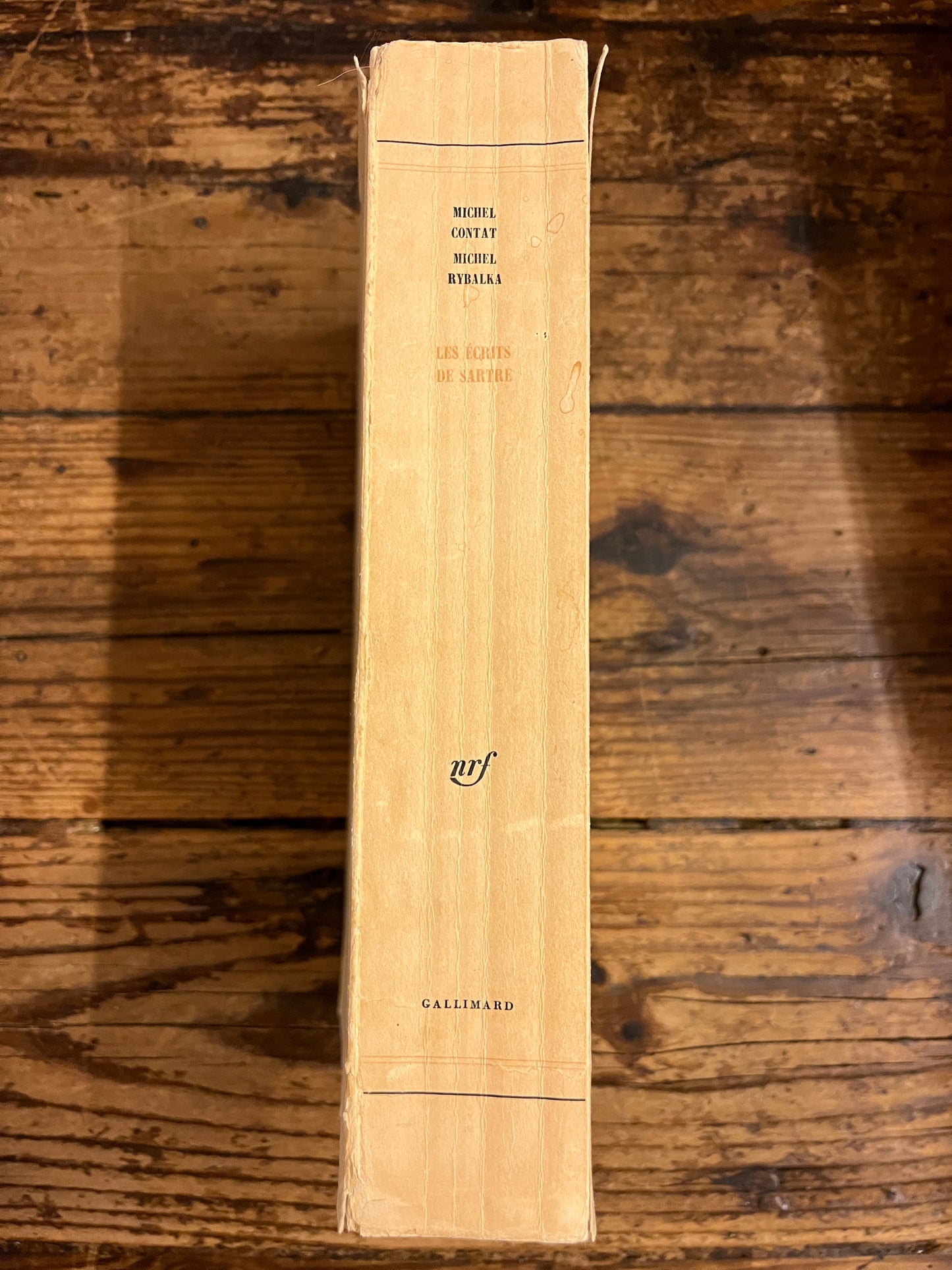 dos du livre "les ecrits de sartre" sur fond de bois
