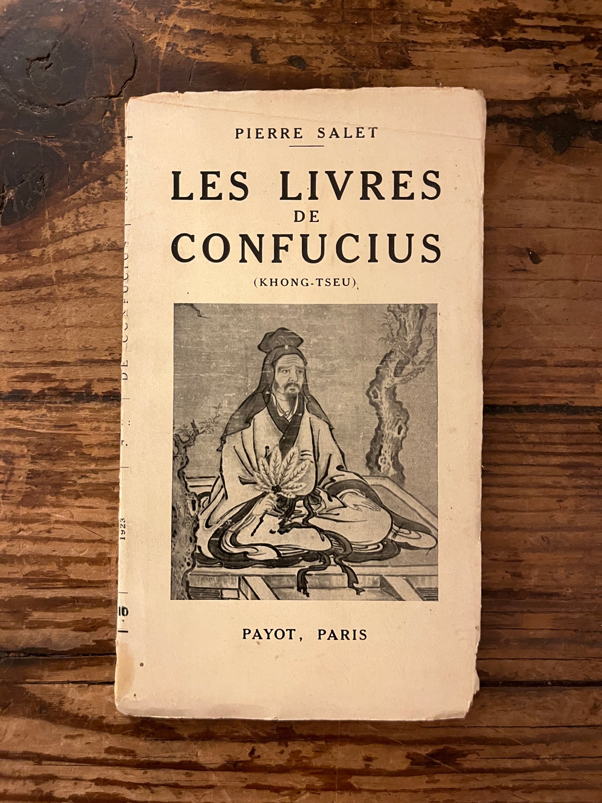 couverture du livre "Les livres de confucius" sur fond de bois