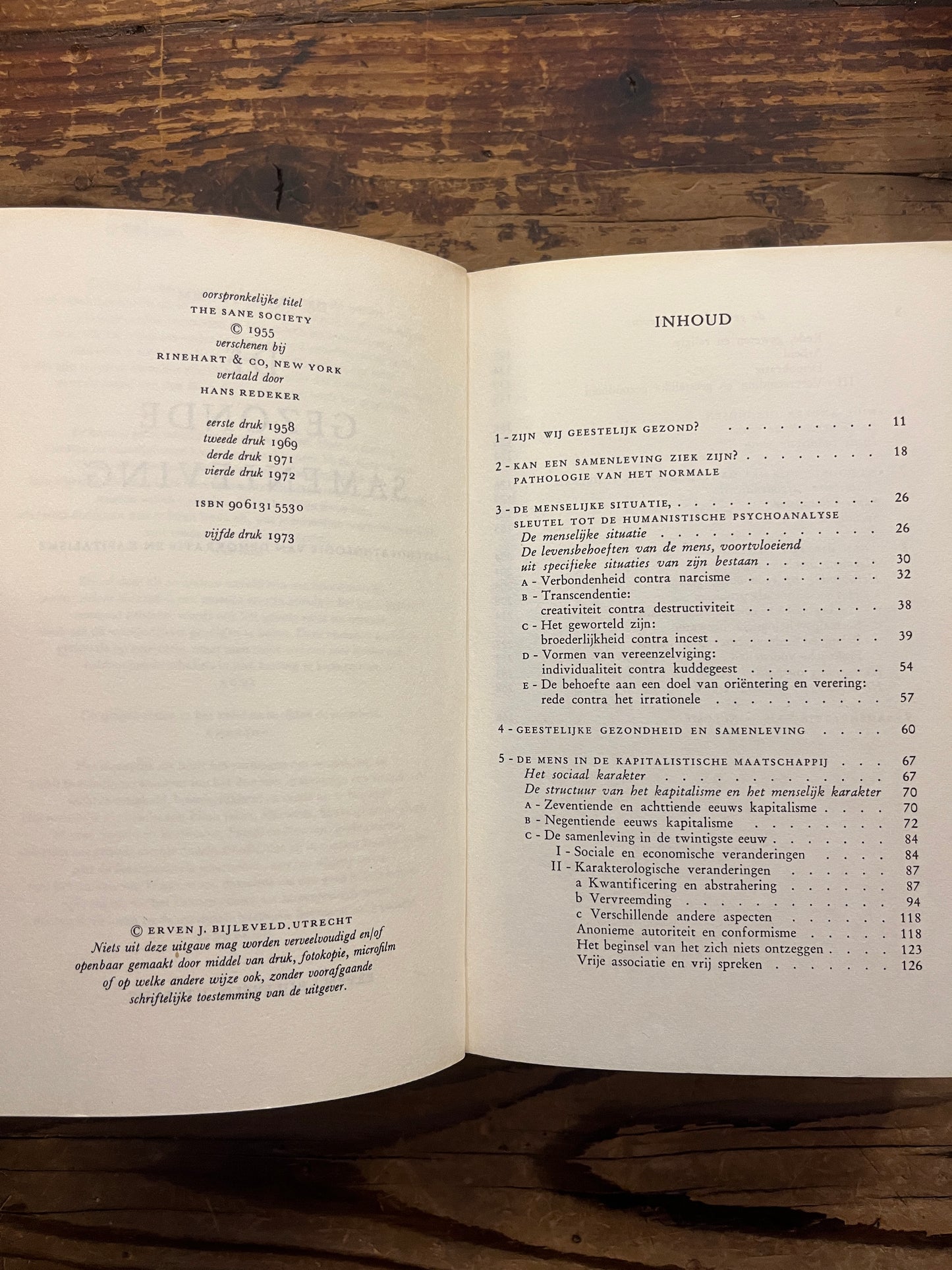 Open boek met de titel 'De gezonde samenleving' door Erich Fromm op een houten achtergrond 