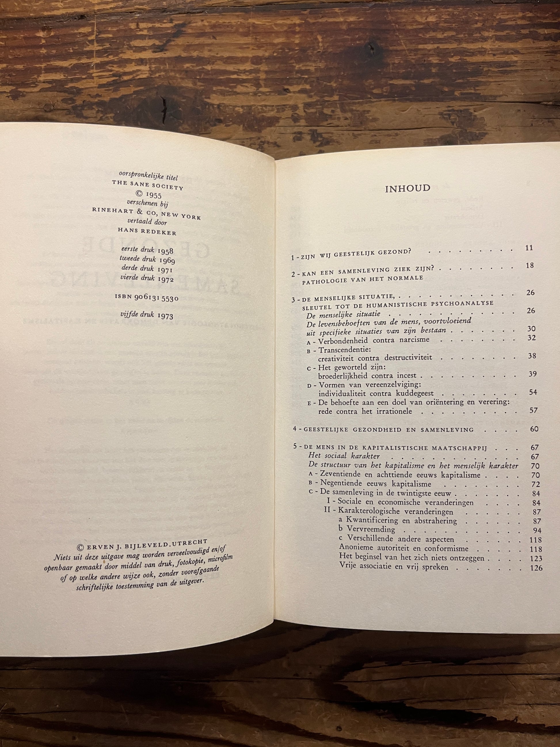 Open boek met de titel 'De gezonde samenleving' door Erich Fromm op een houten achtergrond 