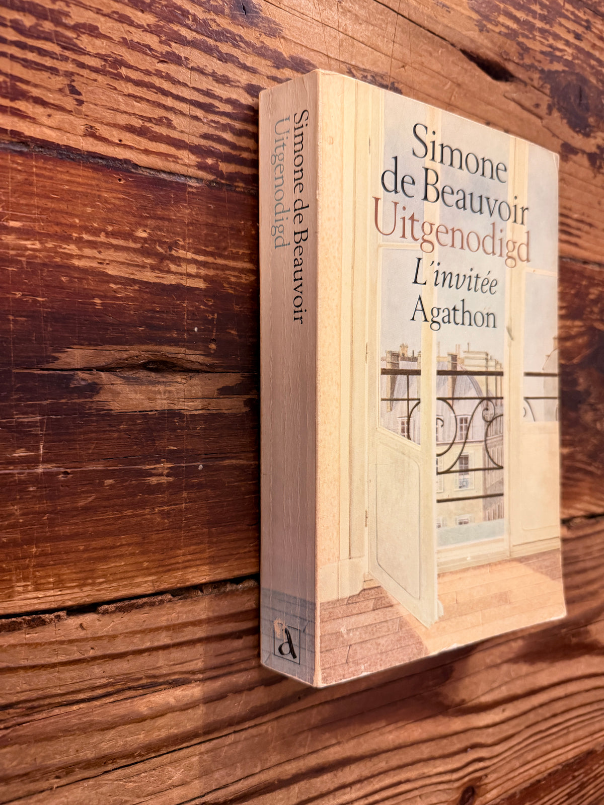 voorkant en rug van boek met de titel 'Uitgenodigd, l'invitée' door Simone de Beauvoir op een houten achtergrond