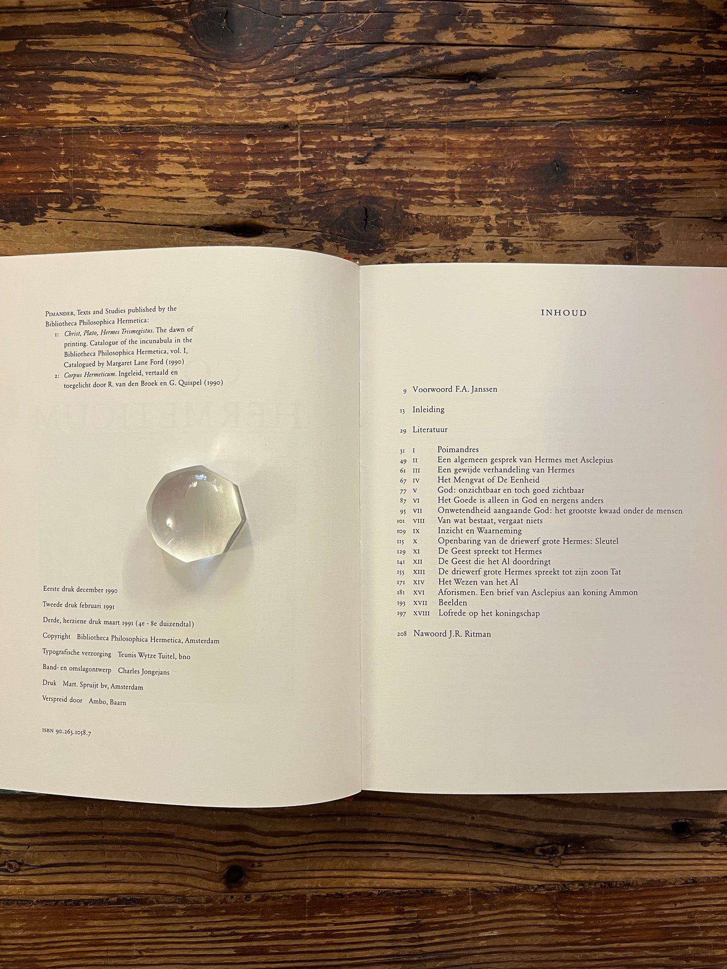 Open boek 'Corpus hermeticum' ingeleid, vertaald en toegelicht door R. van den Broek en G. Quispel, op een houten achtergrond