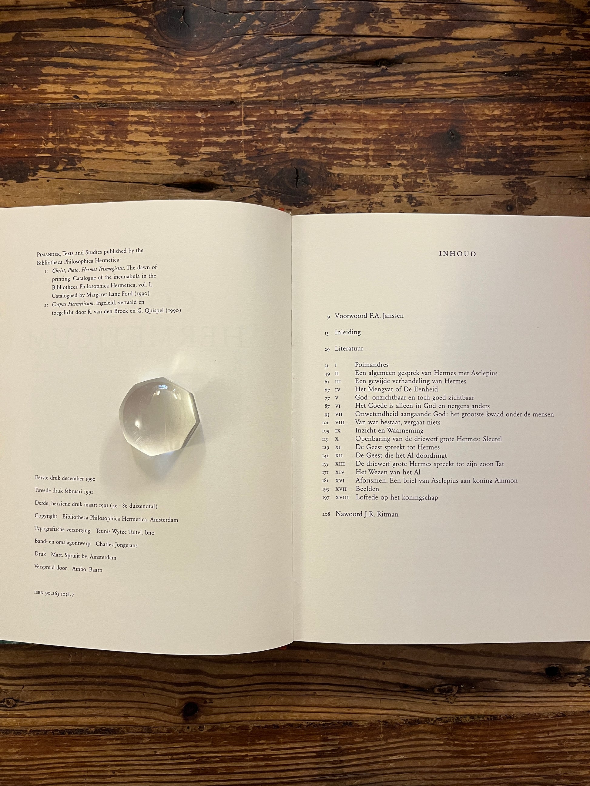 Open boek 'Corpus hermeticum' ingeleid, vertaald en toegelicht door R. van den Broek en G. Quispel, op een houten achtergrond