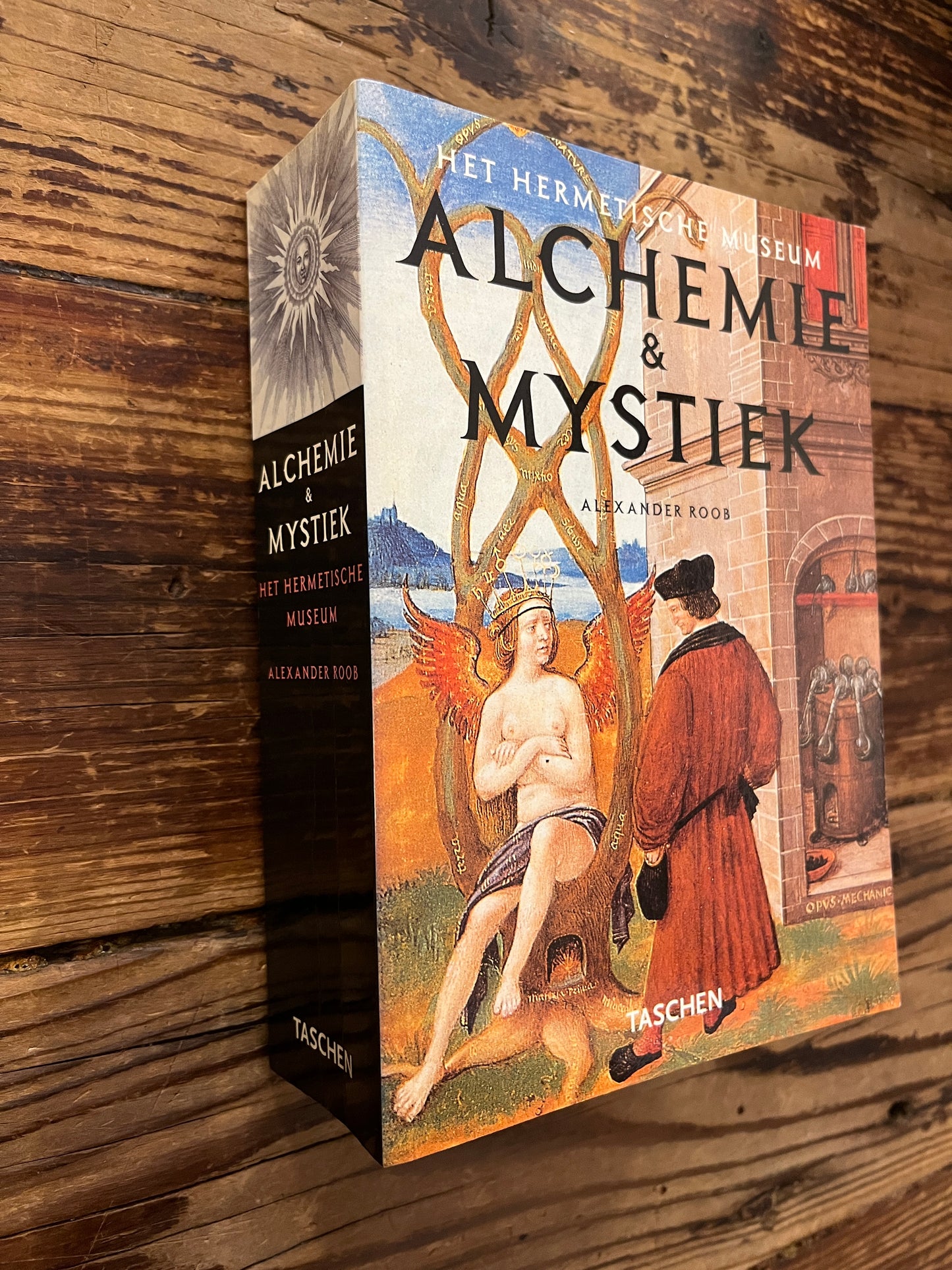Boek met de titel 'Alchemie & Mystiek' door Alexander Roob op een houten achtergrond 
