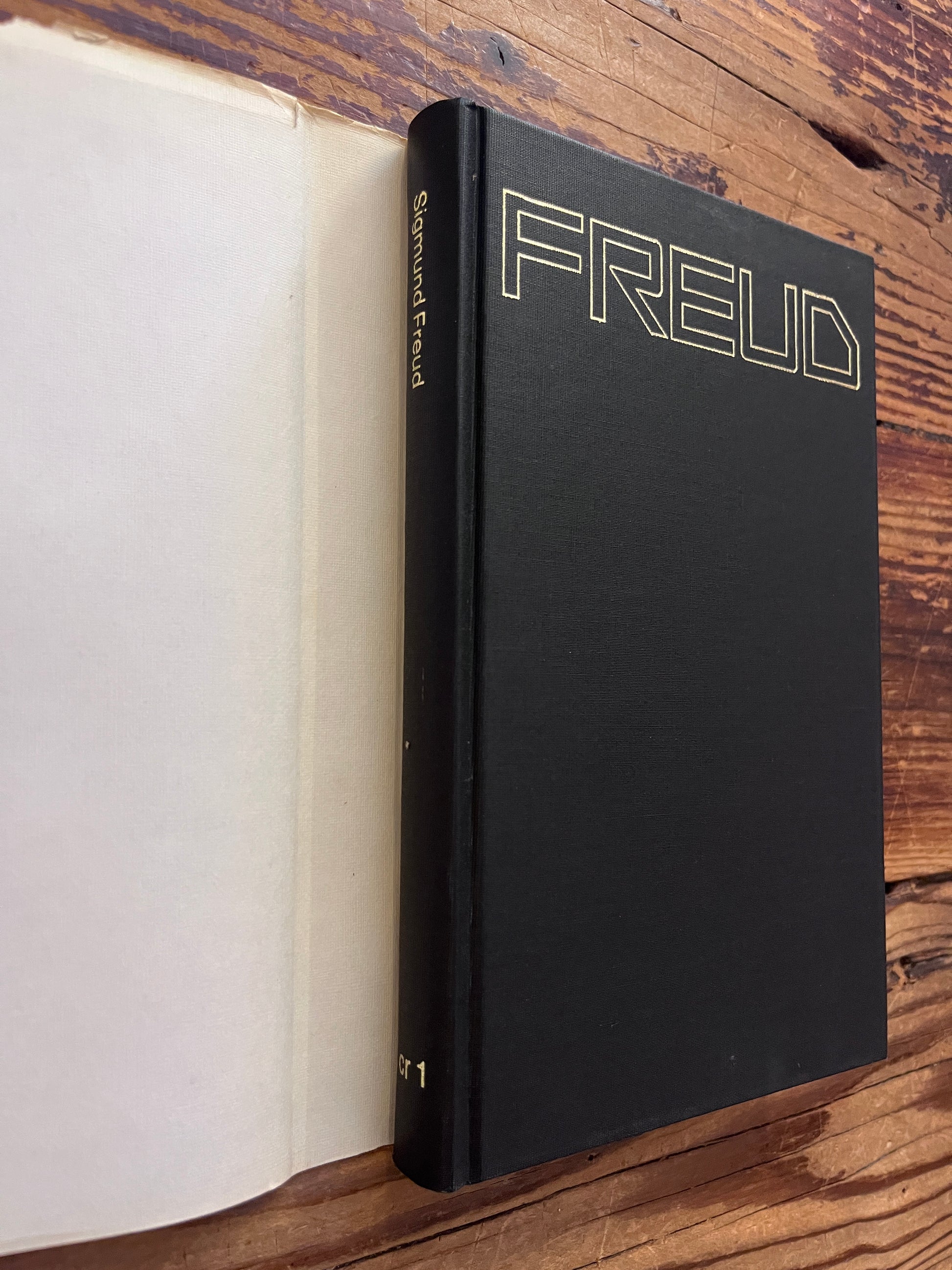 Rug van boek zonder stof omslag met de titel 'Freud, cultuur en religie 1'  door Sigmund Freud op een houten achtergrond 