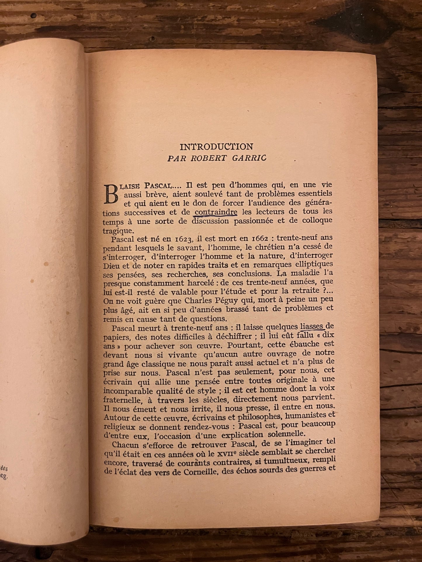 photo d'une page du livre "pensees" sur fond de bois. On y vot qu'un mot y est souligne.