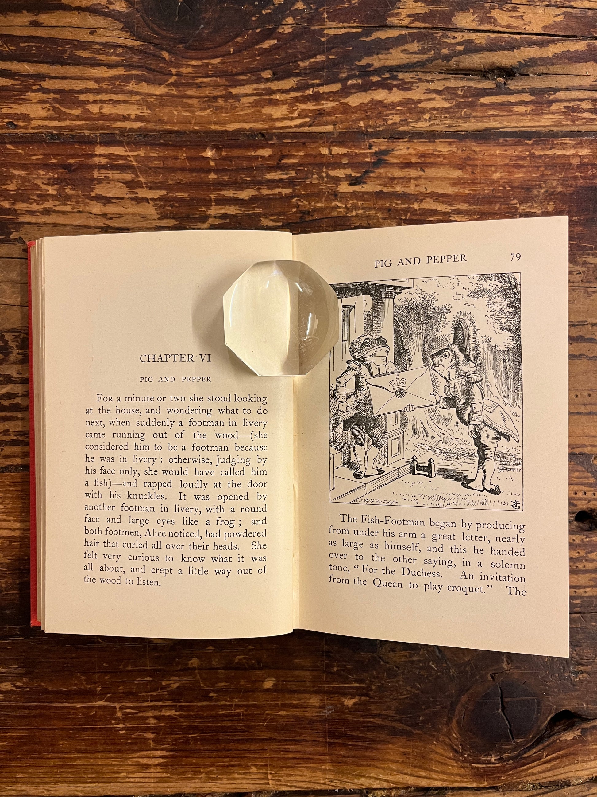 Open book showing John Tenniel's illustration of 'Alice's adventures in wonderland' by Lewis Carroll on a wooden surface