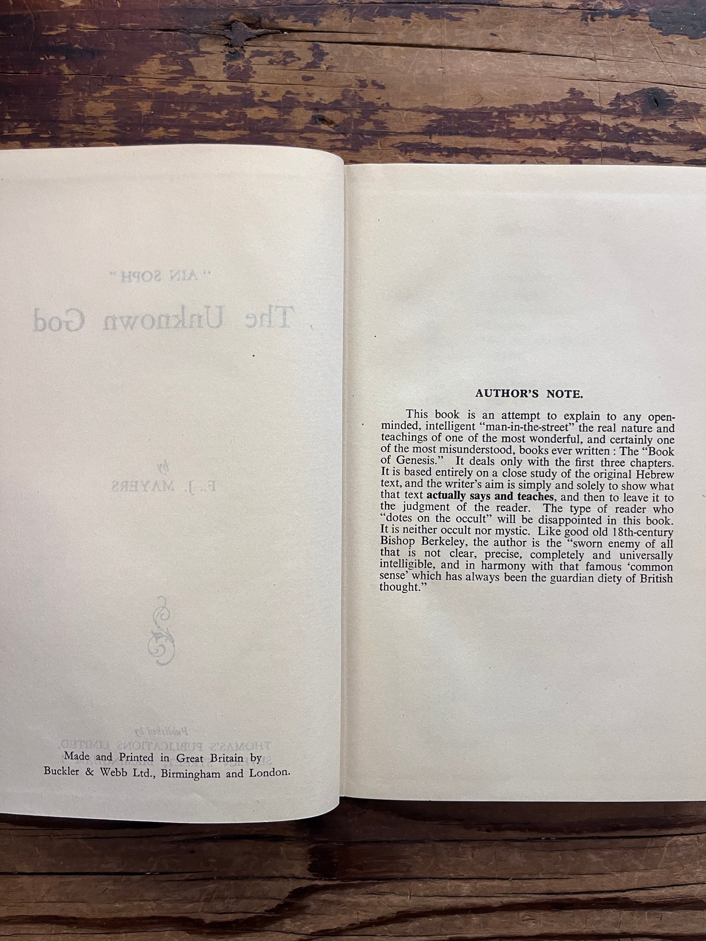 Open book titled 'Ain Soph The Unknown God' by F. J. Mayers on a wooden surface