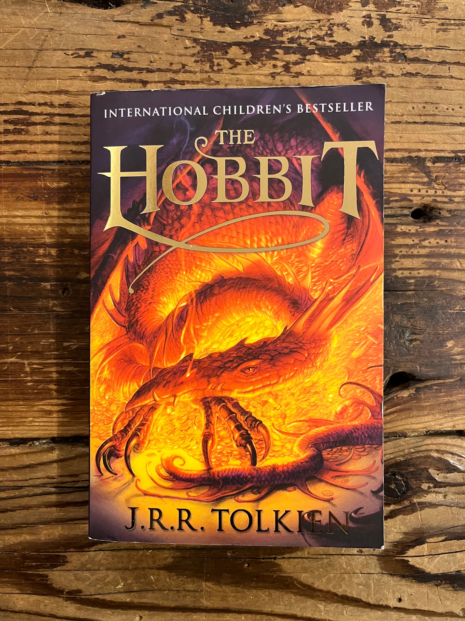 Book cover of 'The Hobbit' by J.R.R. Tolkien on a wooden surface