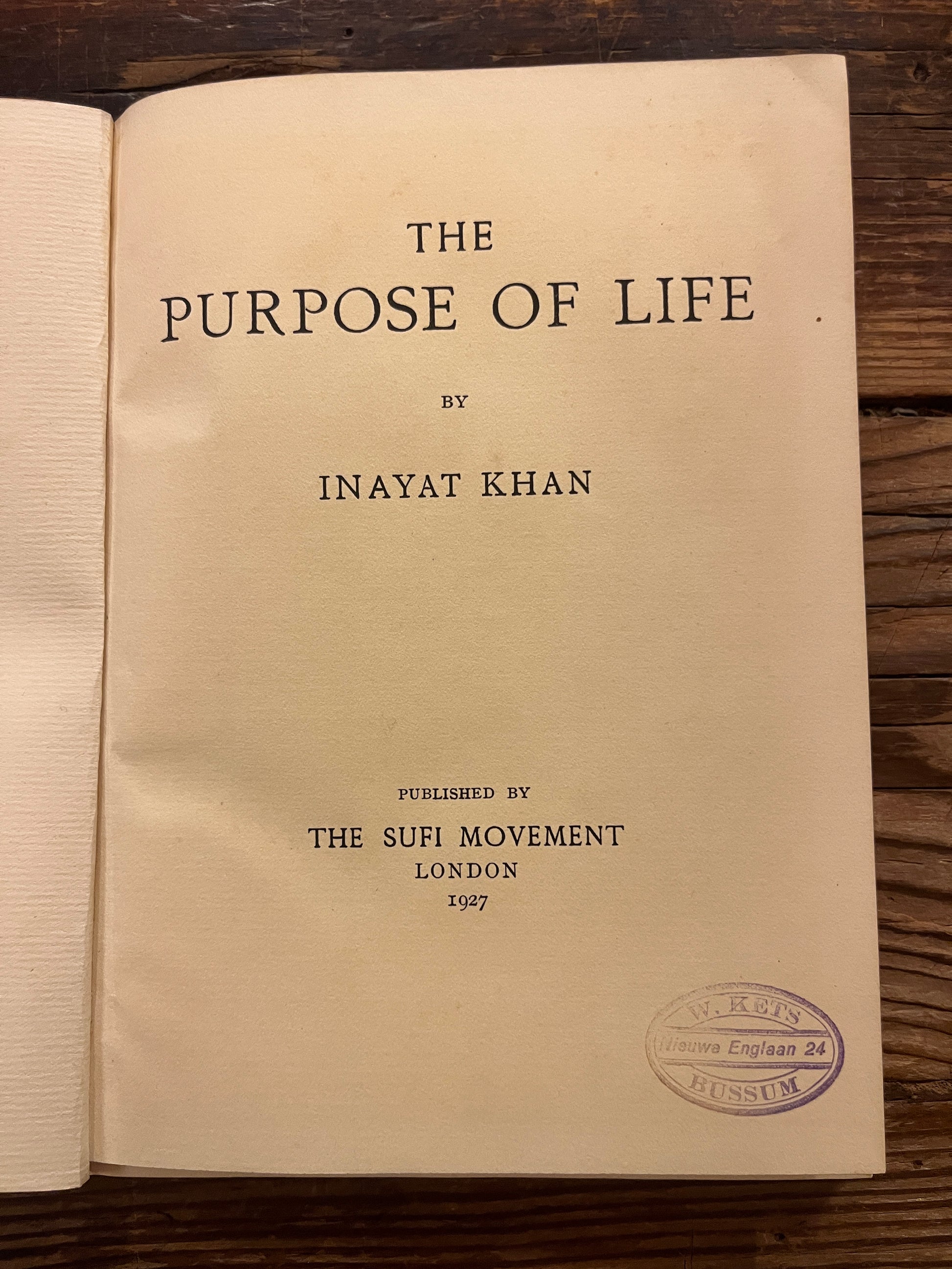 Open book titled 'The Purpose of Life'  by Inayat Khan on a wooden surface