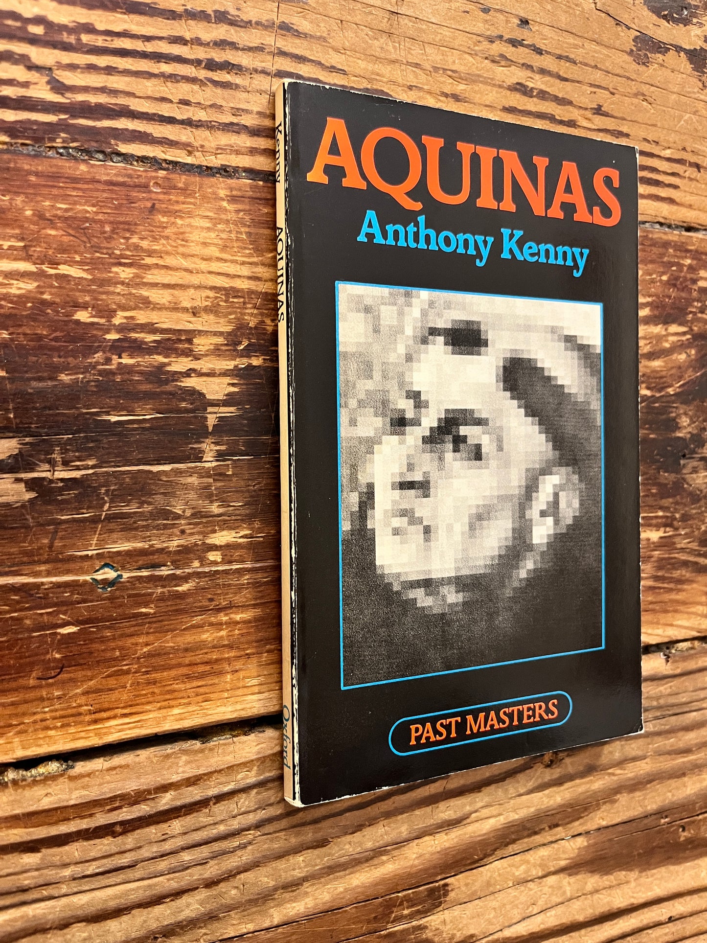 Front cover and spine of book titled 'Aquinas' by Anthony Kenny on a wooden surface