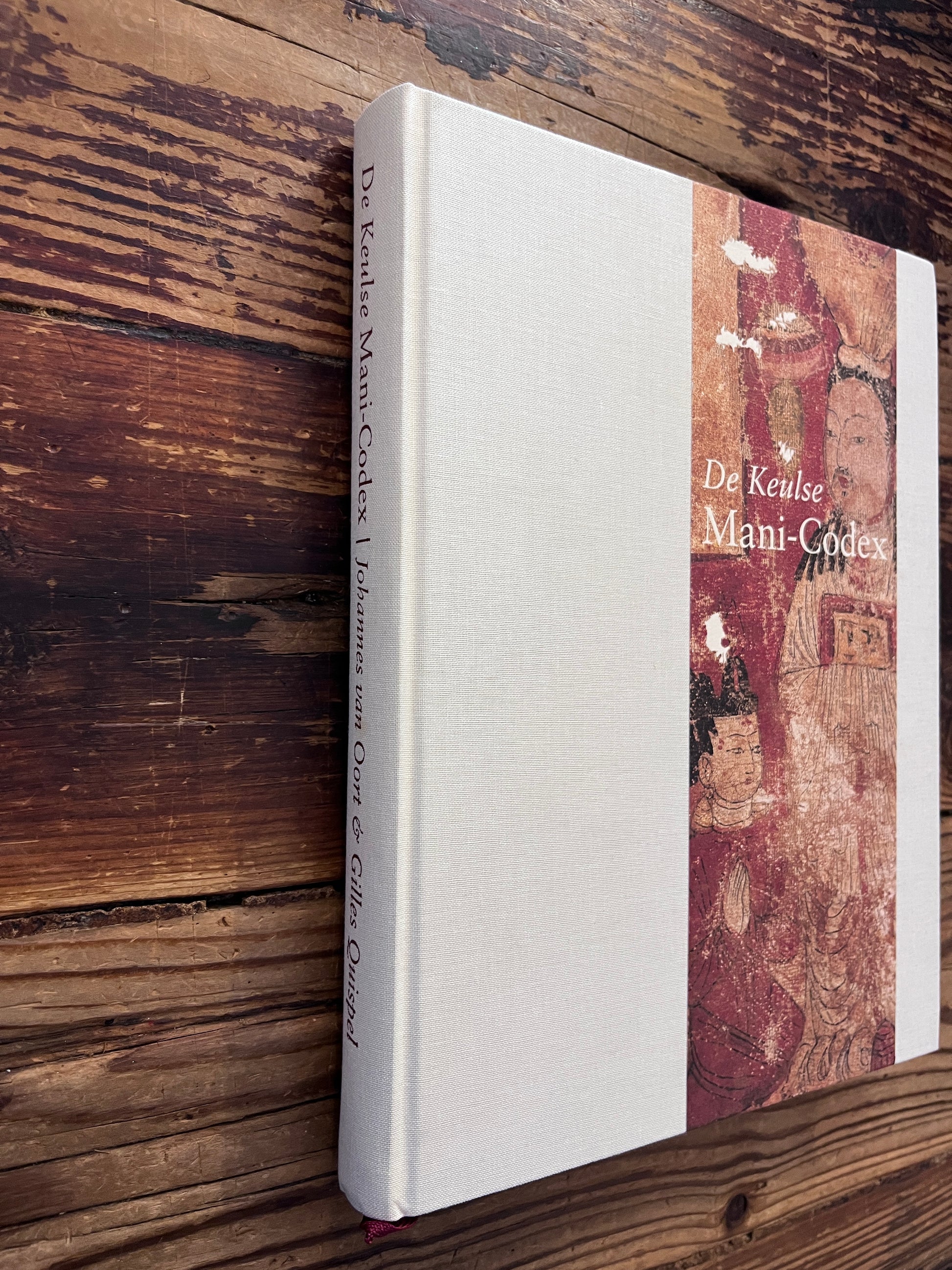 Voorkant en rug van boek met de titel 'de Keulse Mani-Codex' op een houten achtergrond 