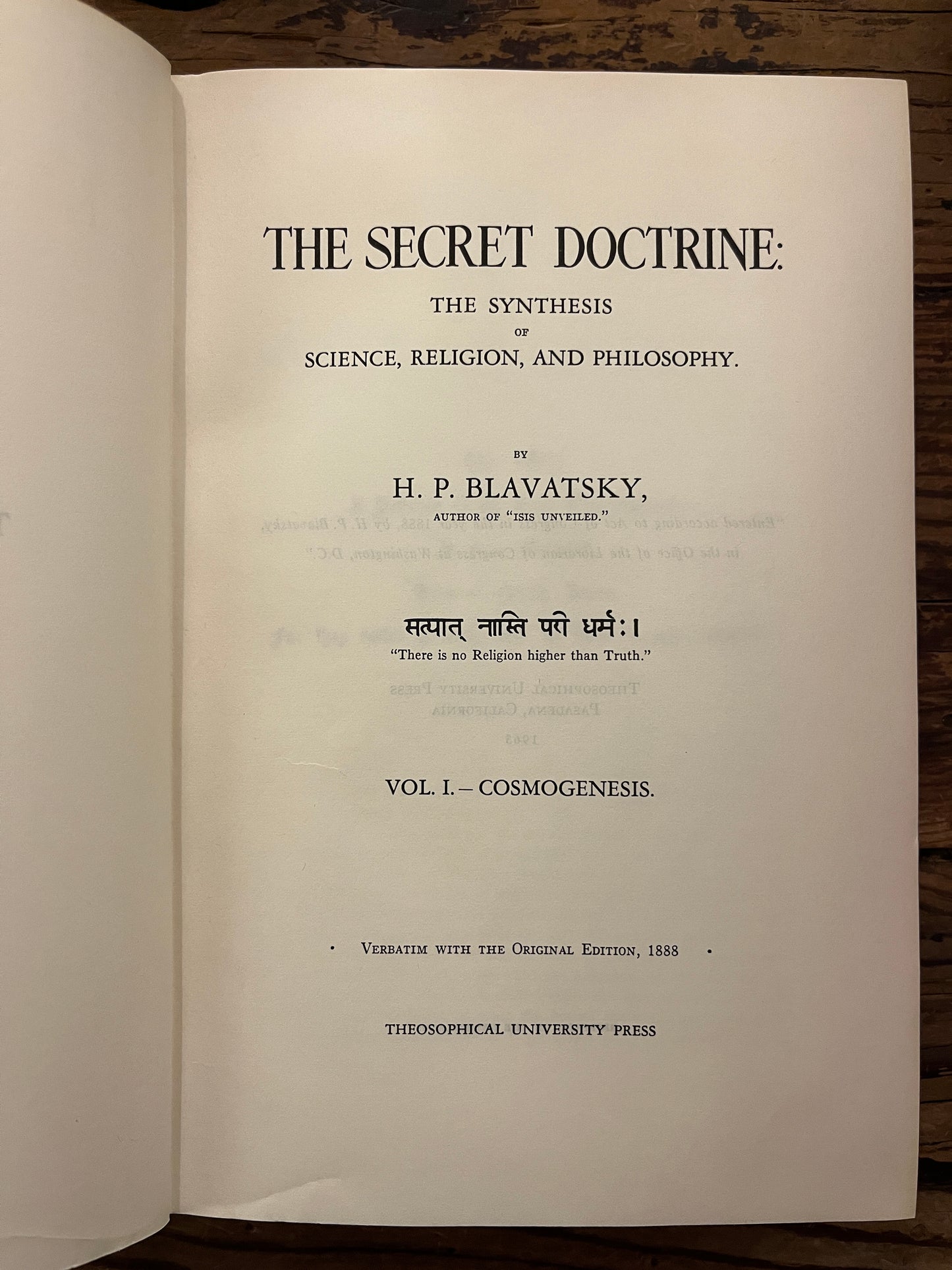 Open book titled 'The Secret Doctrine' by H.P. Blavatsky on a wooden surface.