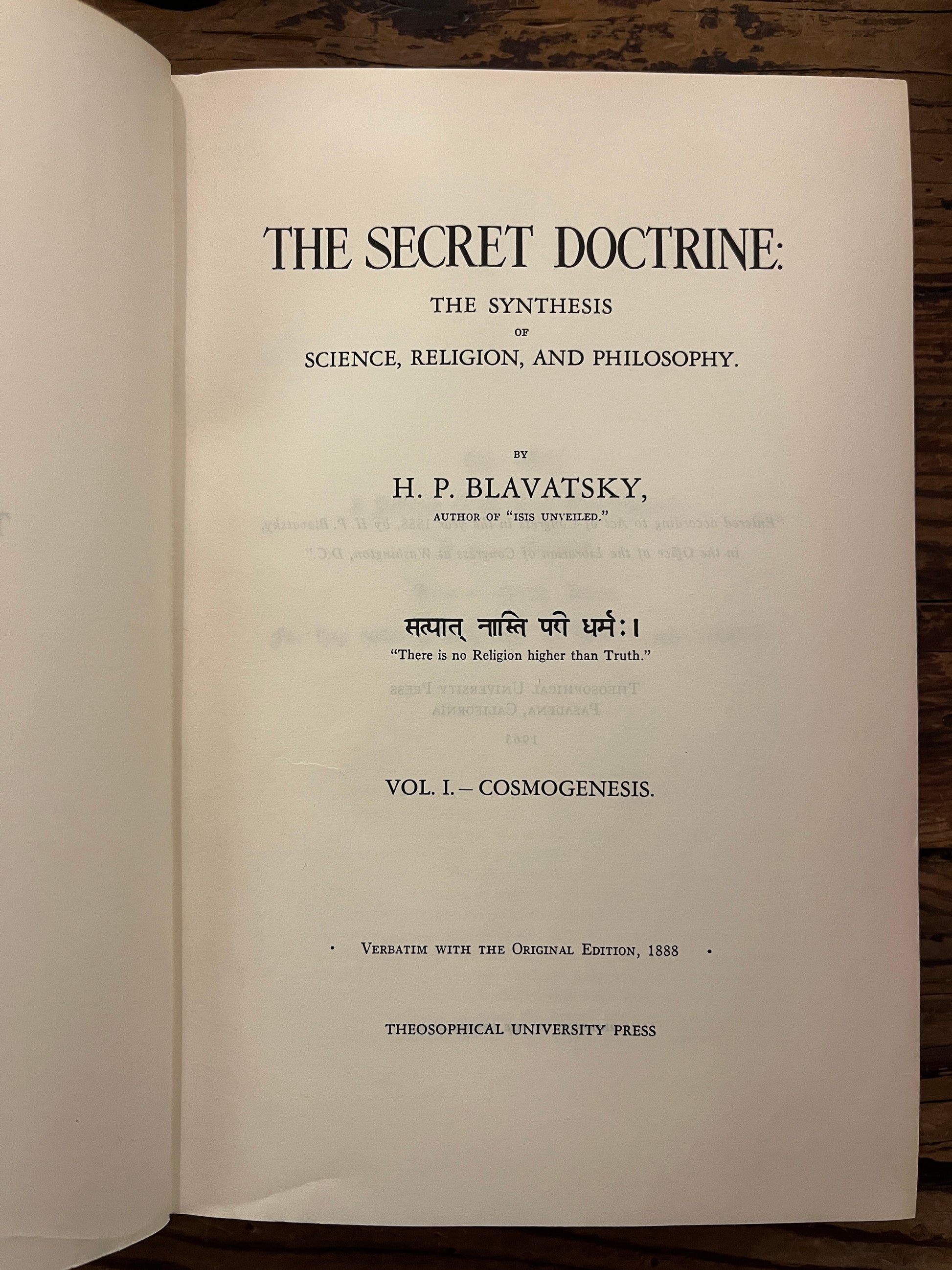 Open book titled 'The Secret Doctrine' by H.P. Blavatsky on a wooden surface.