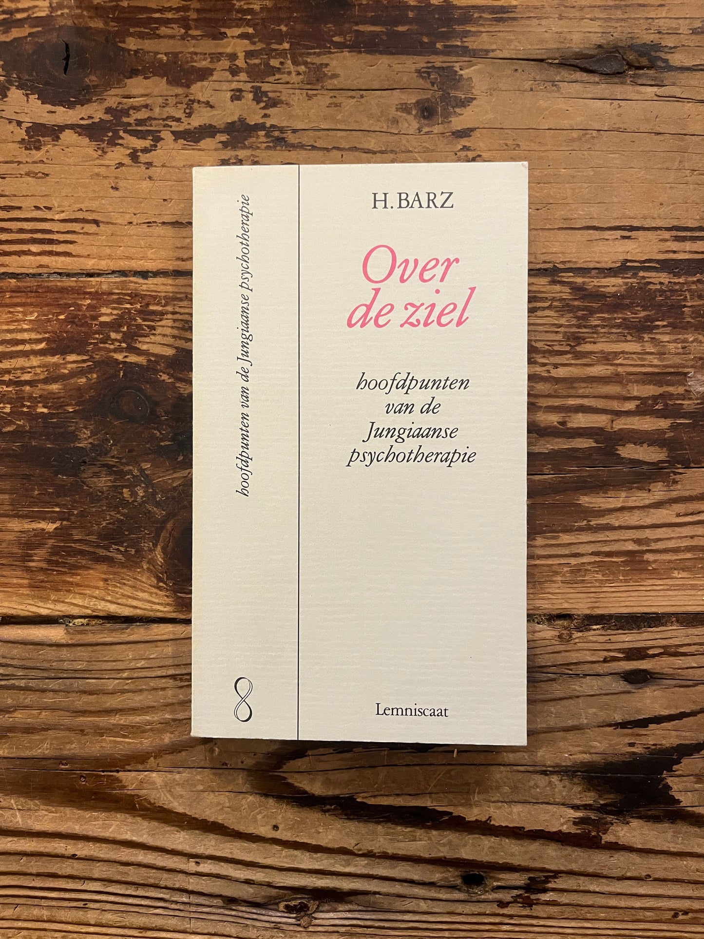 Boek met de titel 'Over de ziel, hoofdpunten in de jungiaanse psychotherapie' door H. Barz op een houten achtergrond 