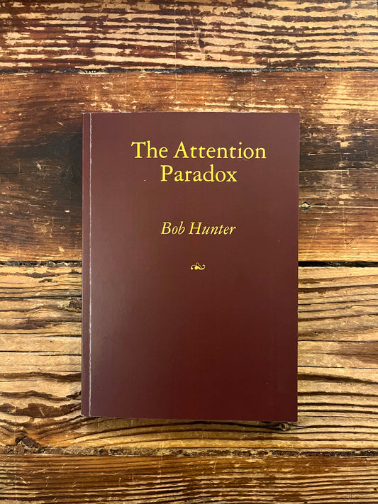 Front cover of book titled 'The Attention Paradox' by Bob Hunter on a wooden surface