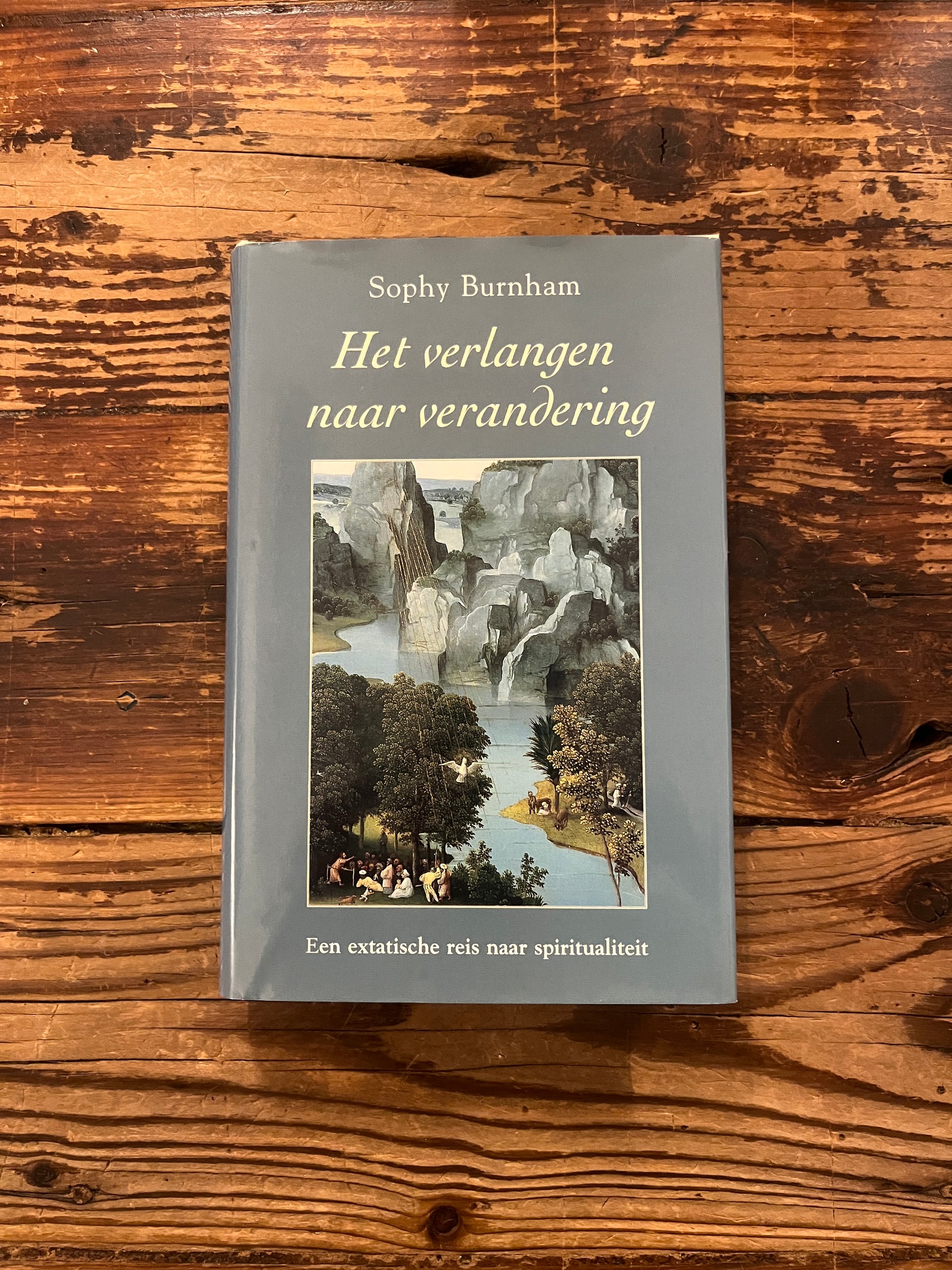 Voorkant van boek met de titel 'het verlangen naar verandering' door Sophy Burnham op een houten achtergrond 