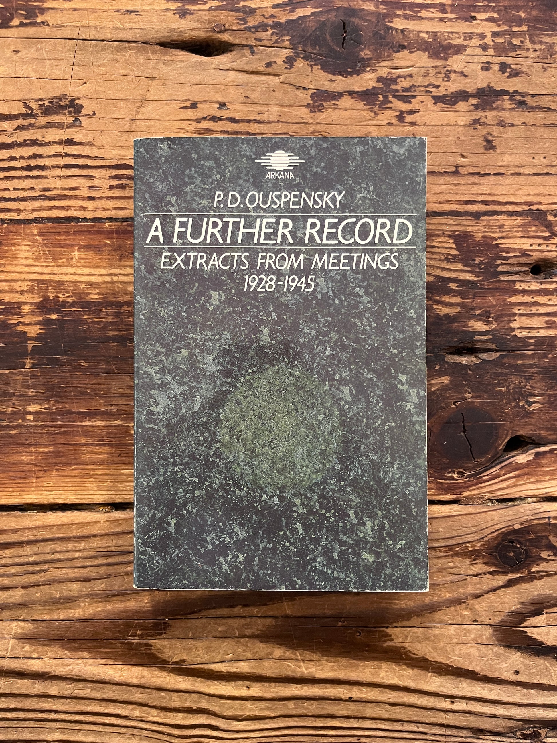 Front cover of a book with the title 'A further record extracts from meetings 1928-1945' by P. D. Ouspensky on a wooden surface