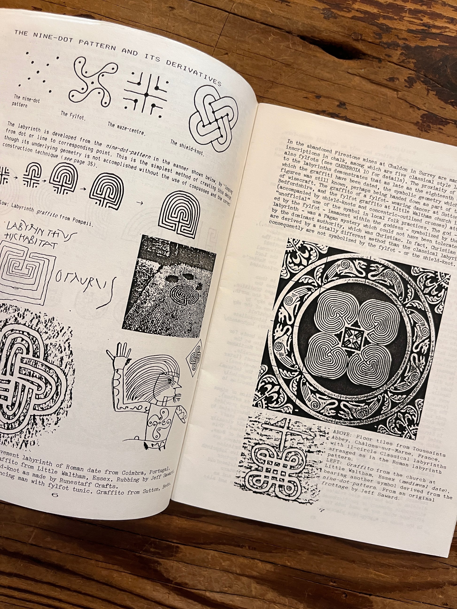 Open booklet with the title 'Labyrinths, their geomancy and symbolism' by Nigel Pennick on a wooden surface 