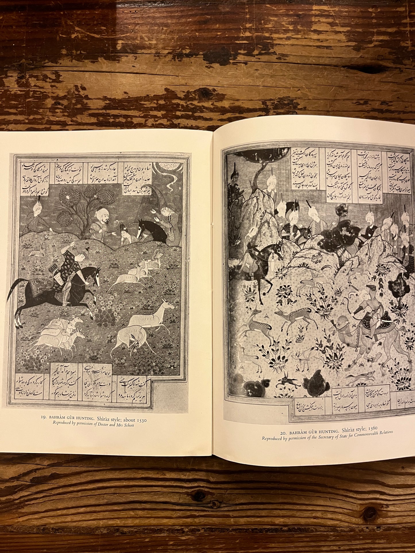 Open book titled 'Persian Paintings' by A.W. Robinson on a wooden surface