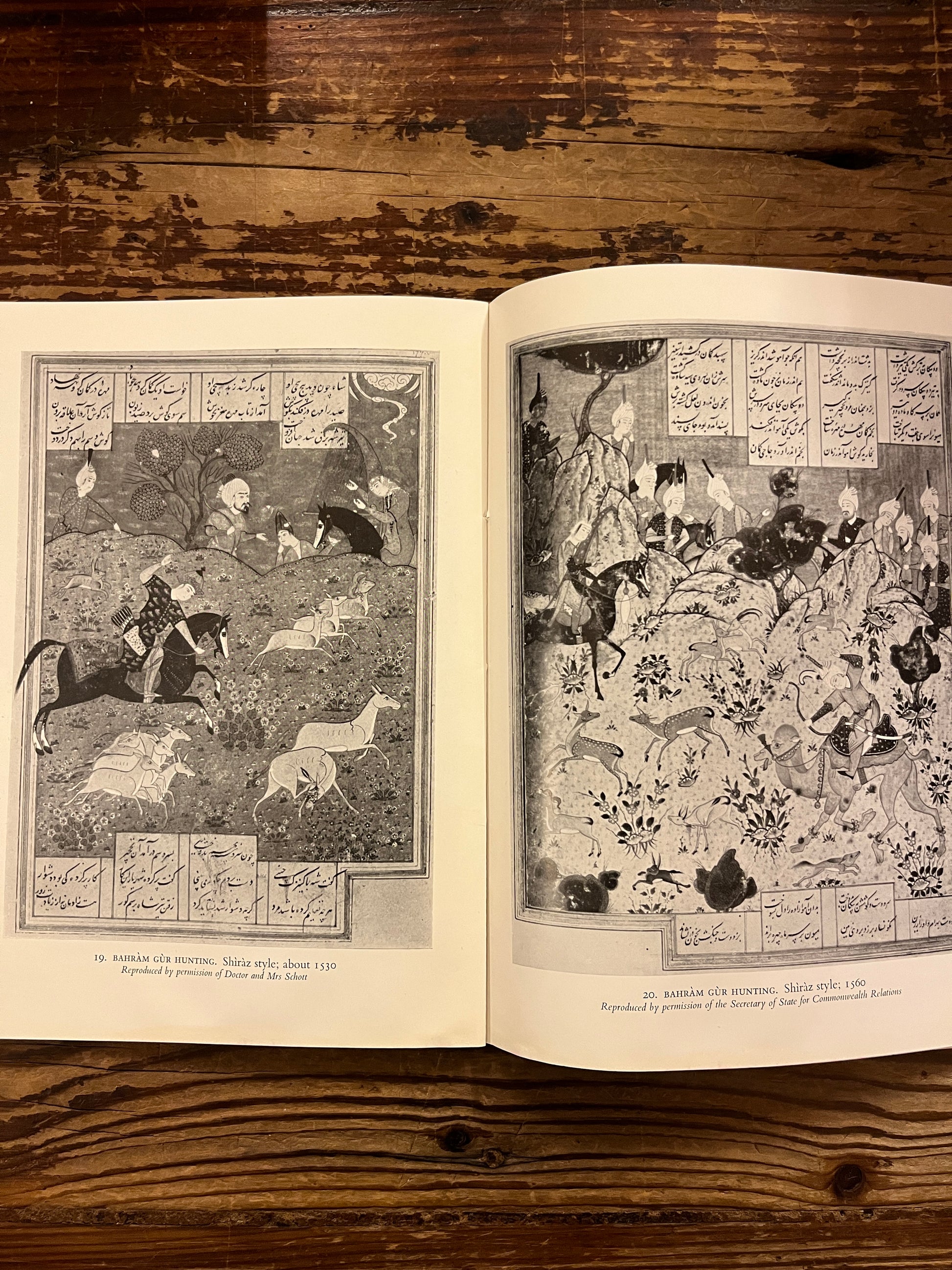 Open book titled 'Persian Paintings' by A.W. Robinson on a wooden surface