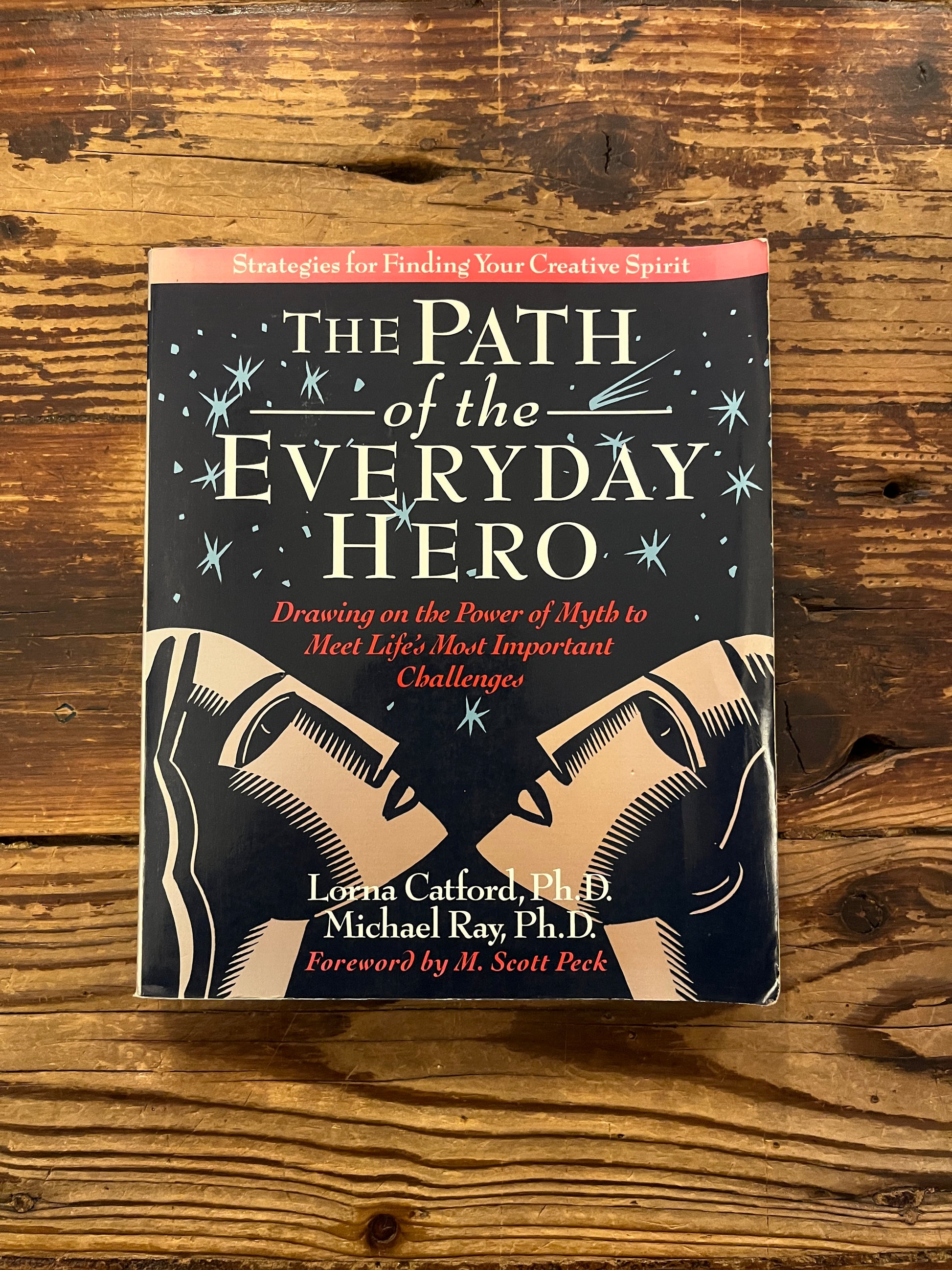 Front cover of book titled 'The Path of the Everyday Hero' on a wooden surface
