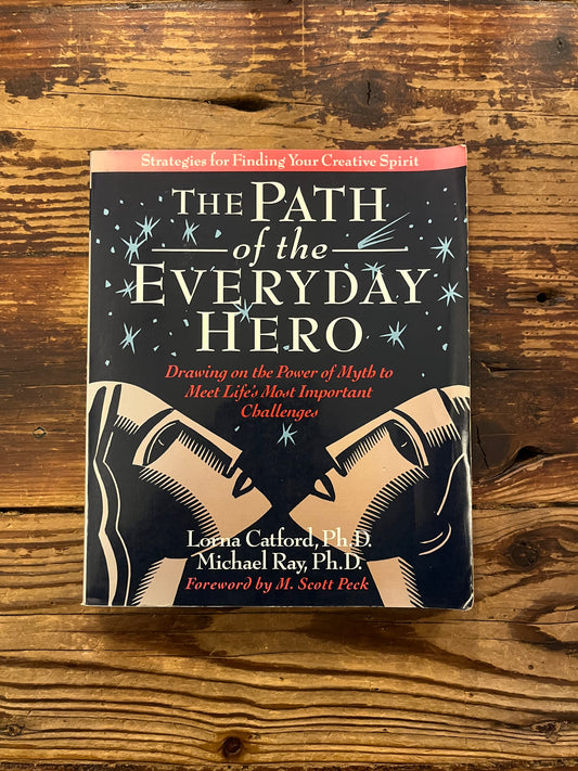 Front cover of book titled 'The Path of the Everyday Hero' on a wooden surface