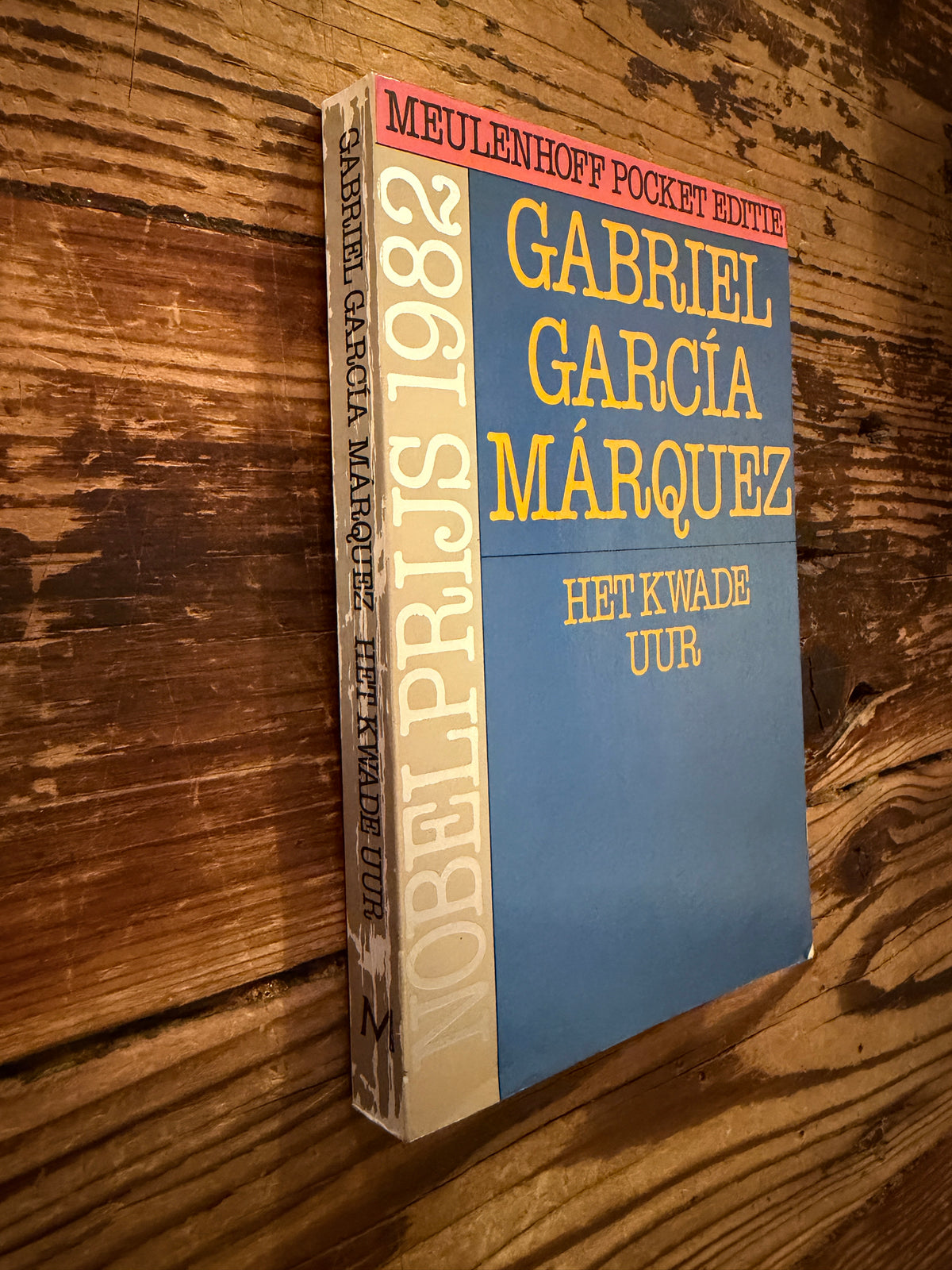 voorkant en rug van boek met de titel 'Het kwade uur' door Gabriel García Márquez op een houten achtergrond 