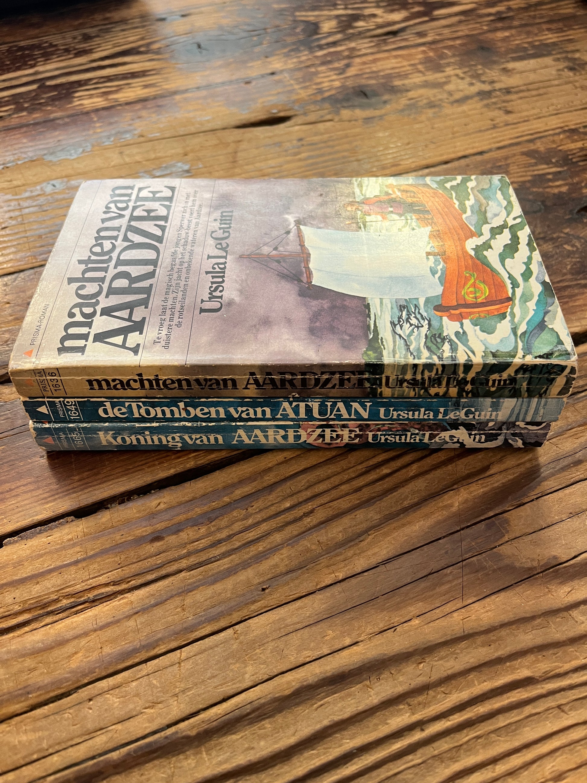 Drie delen van de 'Aardzee' trilogie door Ursula K. Le Guin op een houten achtergrond