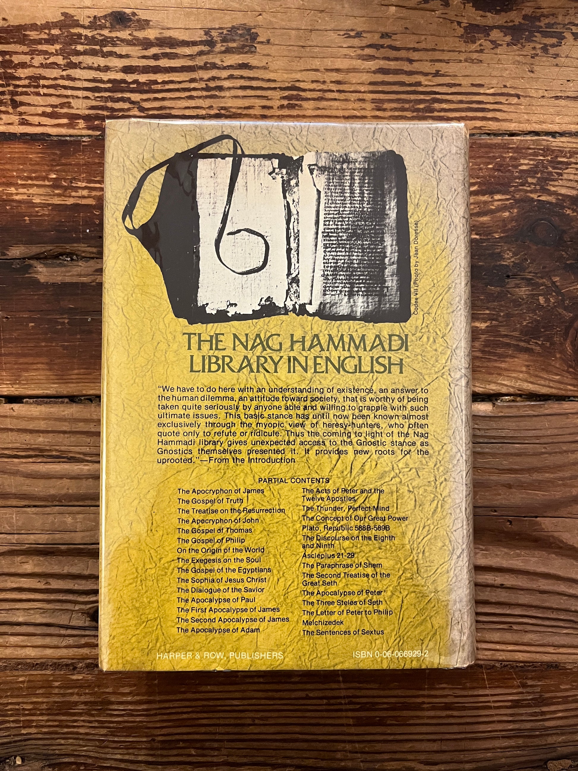 Back cover of book titled 'The Nag Hammadi Library in English' on a wooden surface