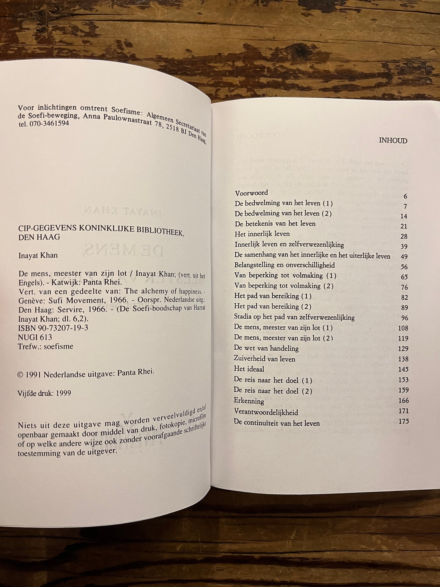 Open boek 'De mens, meester van zijn lot' by Inayat Khan op een houten achtergrond 