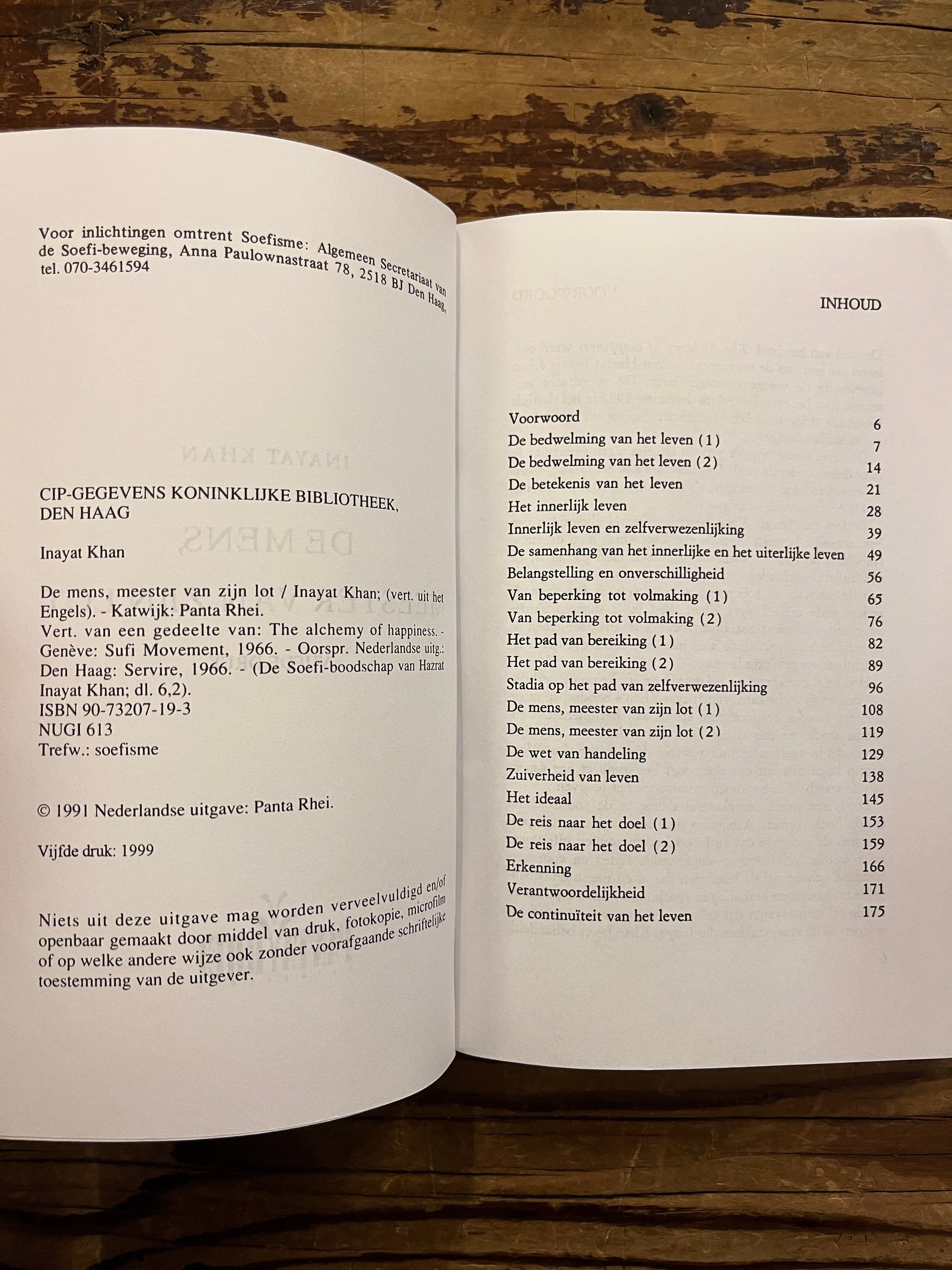 Open boek 'De mens, meester van zijn lot' by Inayat Khan op een houten achtergrond 