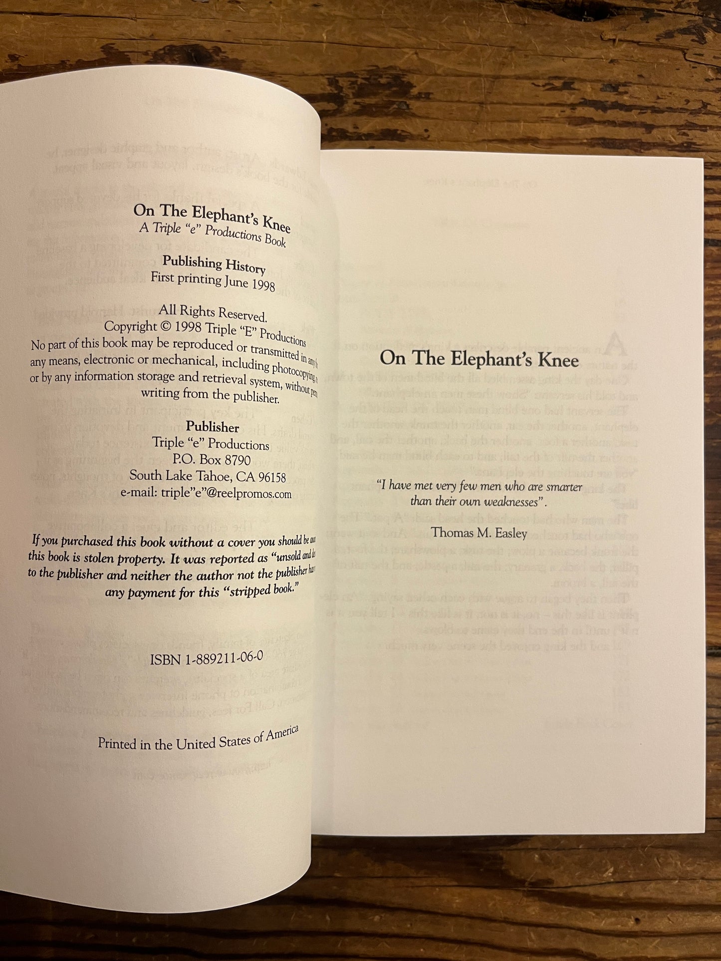 Open book showing the publishers details  of a book titled 'On the Elephant's Knee' on a wooden surface