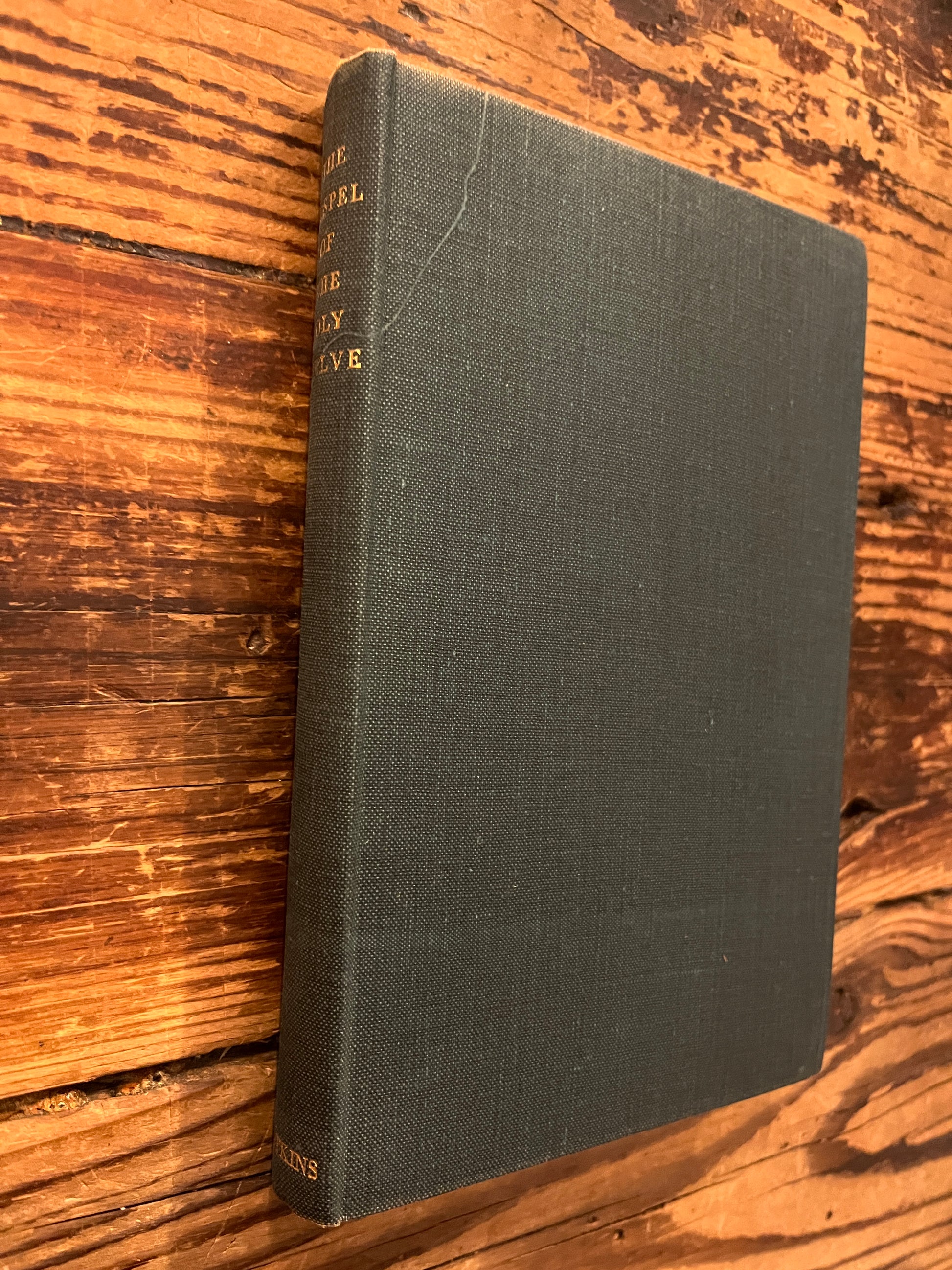 Book titled 'The Gospel of the Holy Twelve' by J.R. Ouseley on a wooden surface