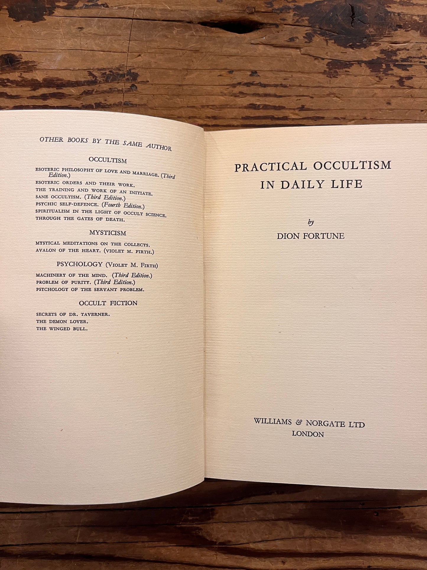 Open rare book with the title 'practical occultism' by Dion Fortune on a wooden surface 