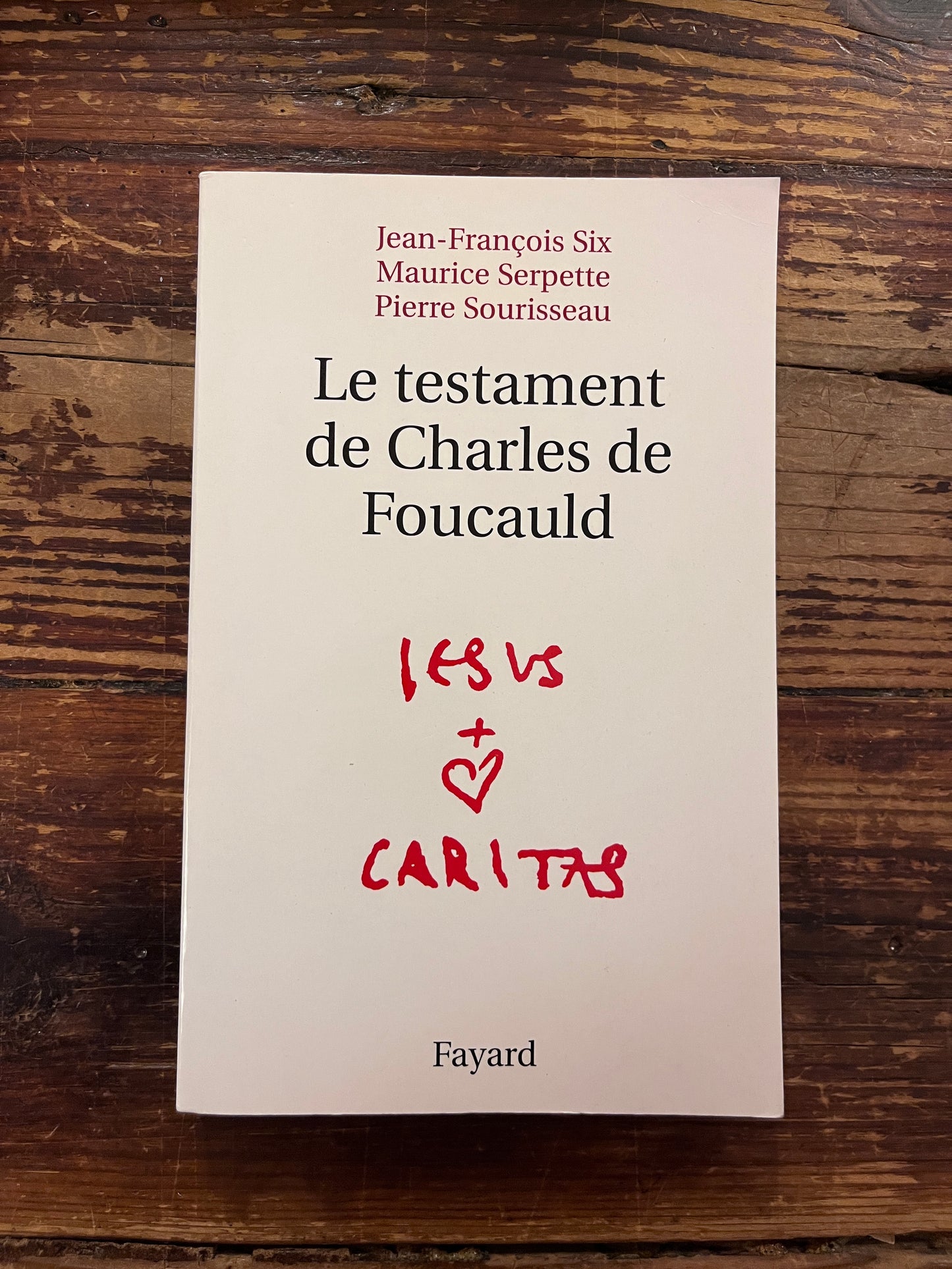 photo de la couverture du livre "le testament de charles de foucauld"sur fond de bois