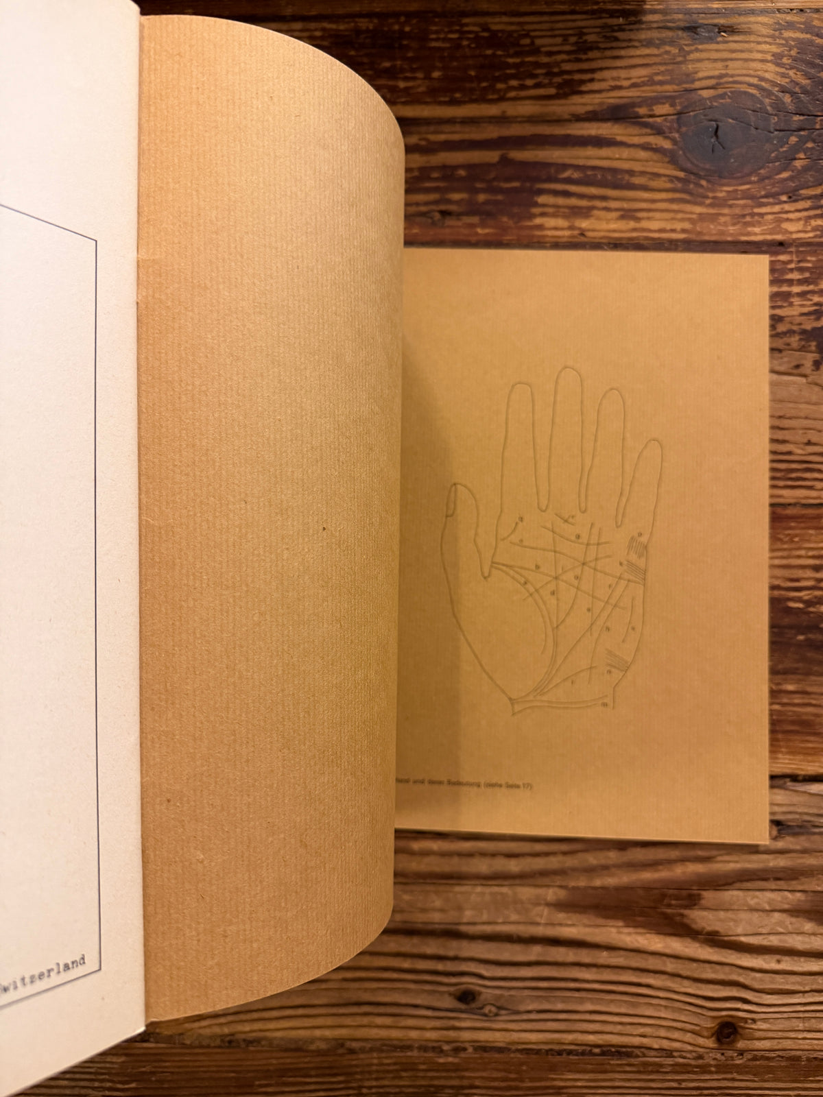 last page of the paperback of 'Simmen's Portfolio No. 1: Die glückliche Hand' on a wooden background 
