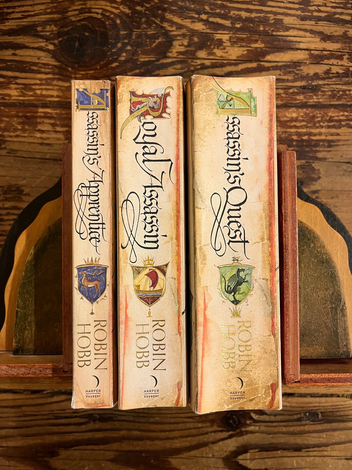 Three books by Robin Hobb titled 'Assassin's Quest', 'Royal Assassin', and 'Assassin's Apprentice' on a wooden surface.