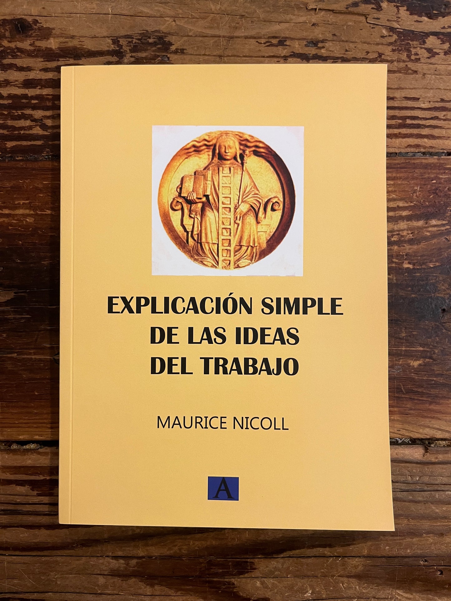 front cover of the book titled 'explicacion simple de las ideas del trabajo' by Maurice Nicoll on a wooden surface 